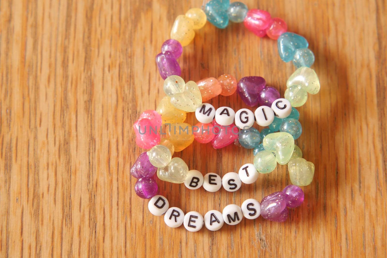 Brightly colored beads spell out uplifting words on a wooden table.
