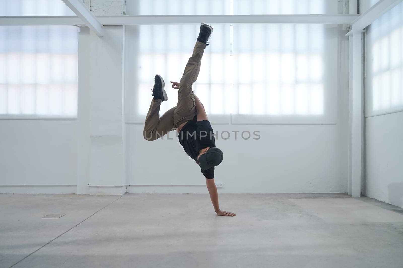 In a bright and spacious studio, a highly skilled breakdancer showcases their impressive dance talents