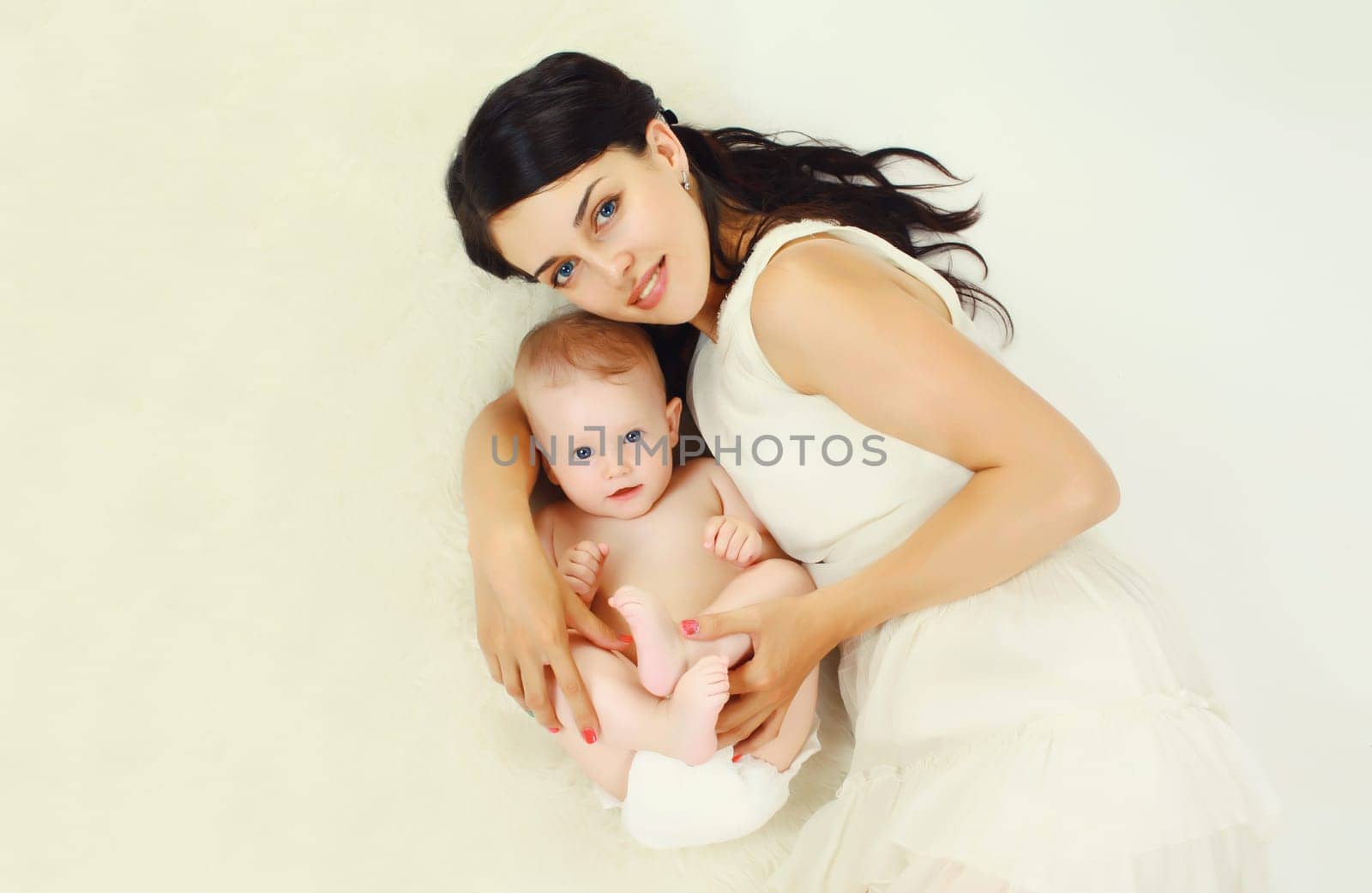 happy young mother lying with baby together on the floor at home