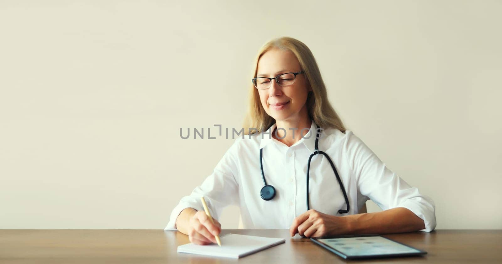 Caucasian middle-aged woman doctor working sitting at desk in clinic office