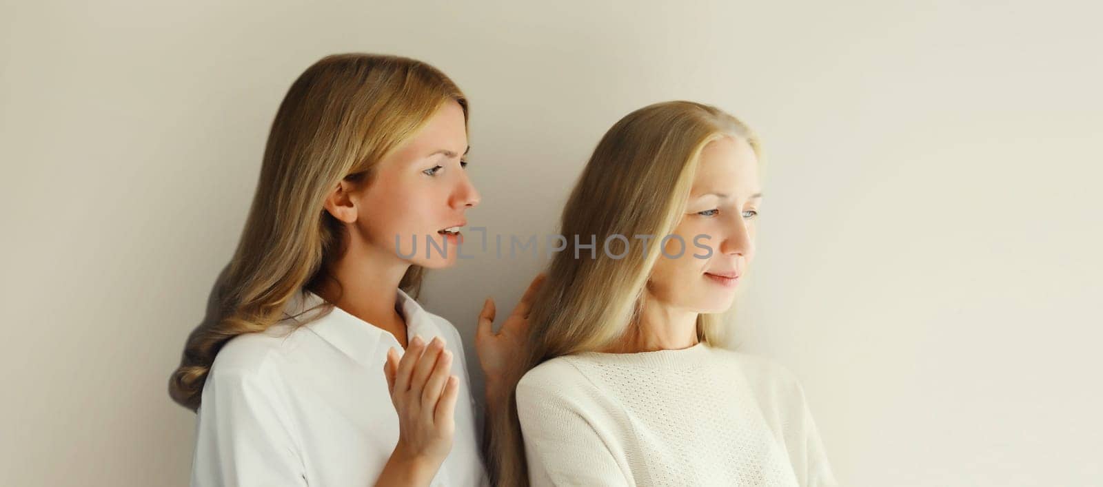 Upset offended caucasian middle aged mother or sister and adult daughter together on studio background