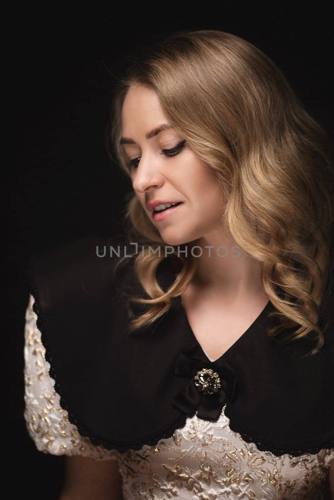 Beautiful blonde in a dress, portrait on a black background.