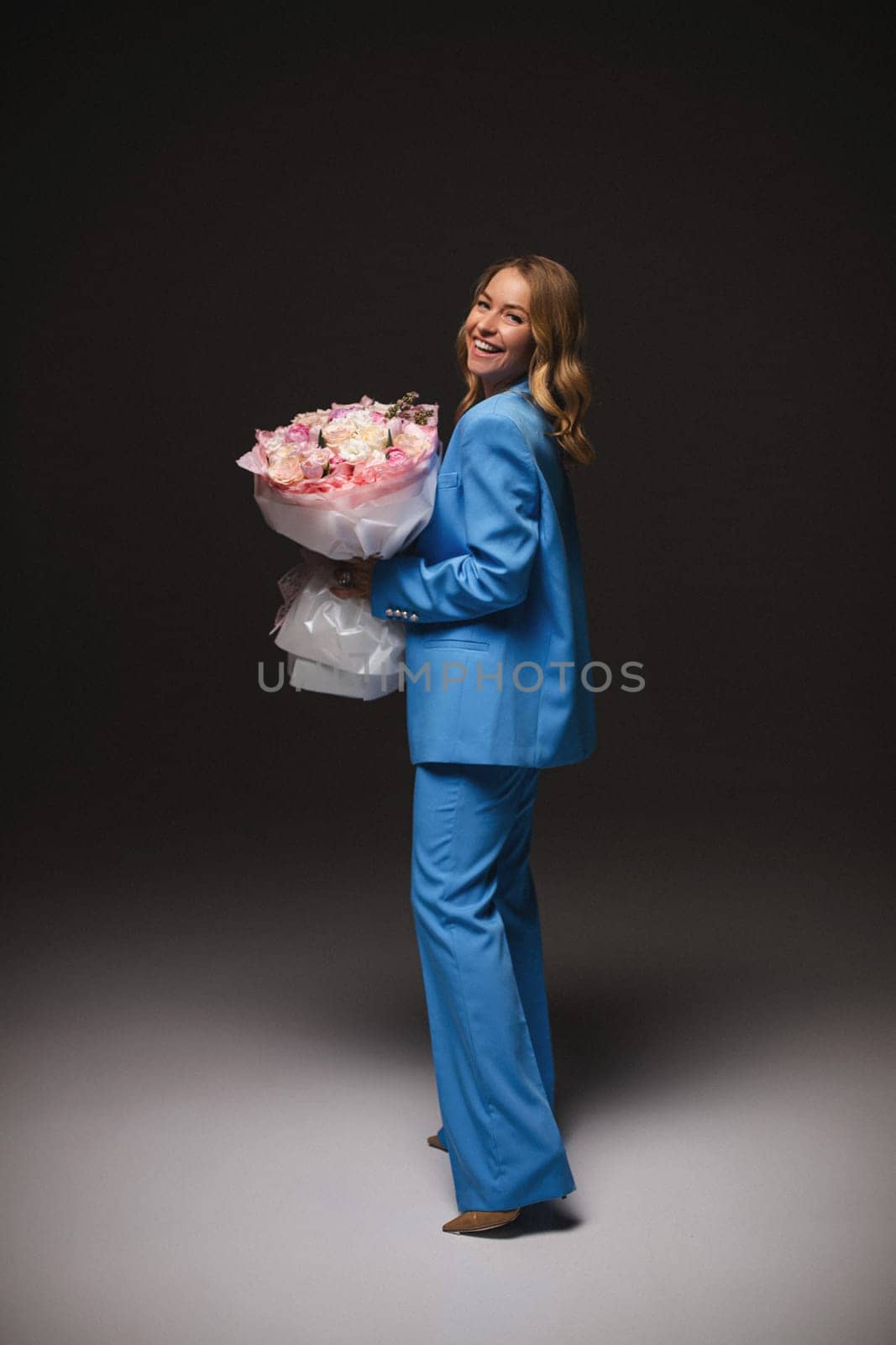 Beautiful girl fashion model with soft pink makeup poses in an elegant blue pantsuit. Fashion and beauty.