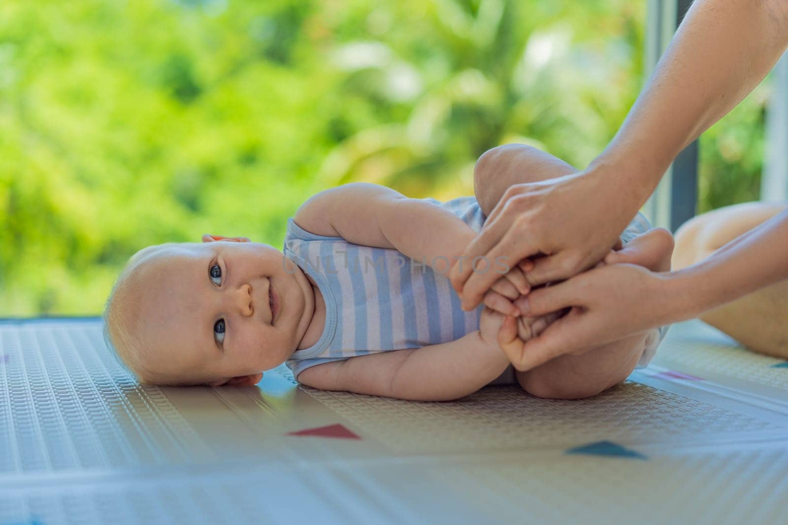 A mother practices baby gymnastics with her 3-month-old on a soft children's play mat. A joyful and nurturing moment focused on bonding, development, and care. Early childhood, fitness, and parenting concept.