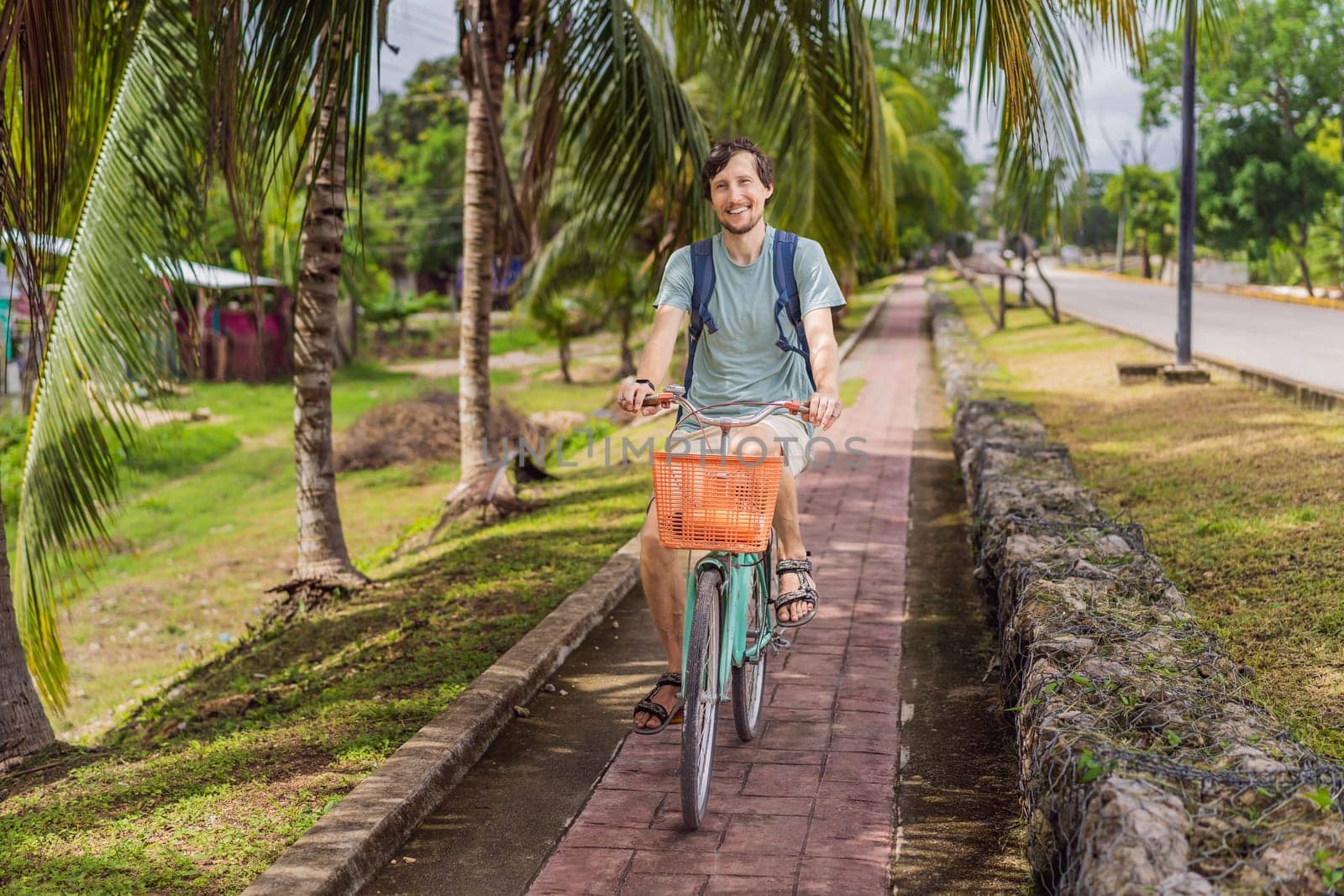 Man tourist cycling through the charming village of Bacalar, Mexico. Quintana Roo travel, scenic bike paths, and eco-friendly exploration concept.