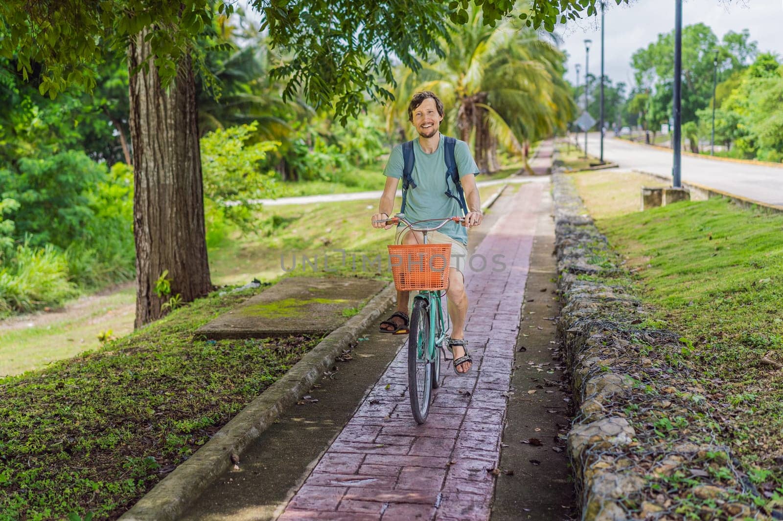 Man tourist cycling through the charming village of Bacalar, Mexico. Quintana Roo travel, scenic bike paths, and eco-friendly exploration concept.