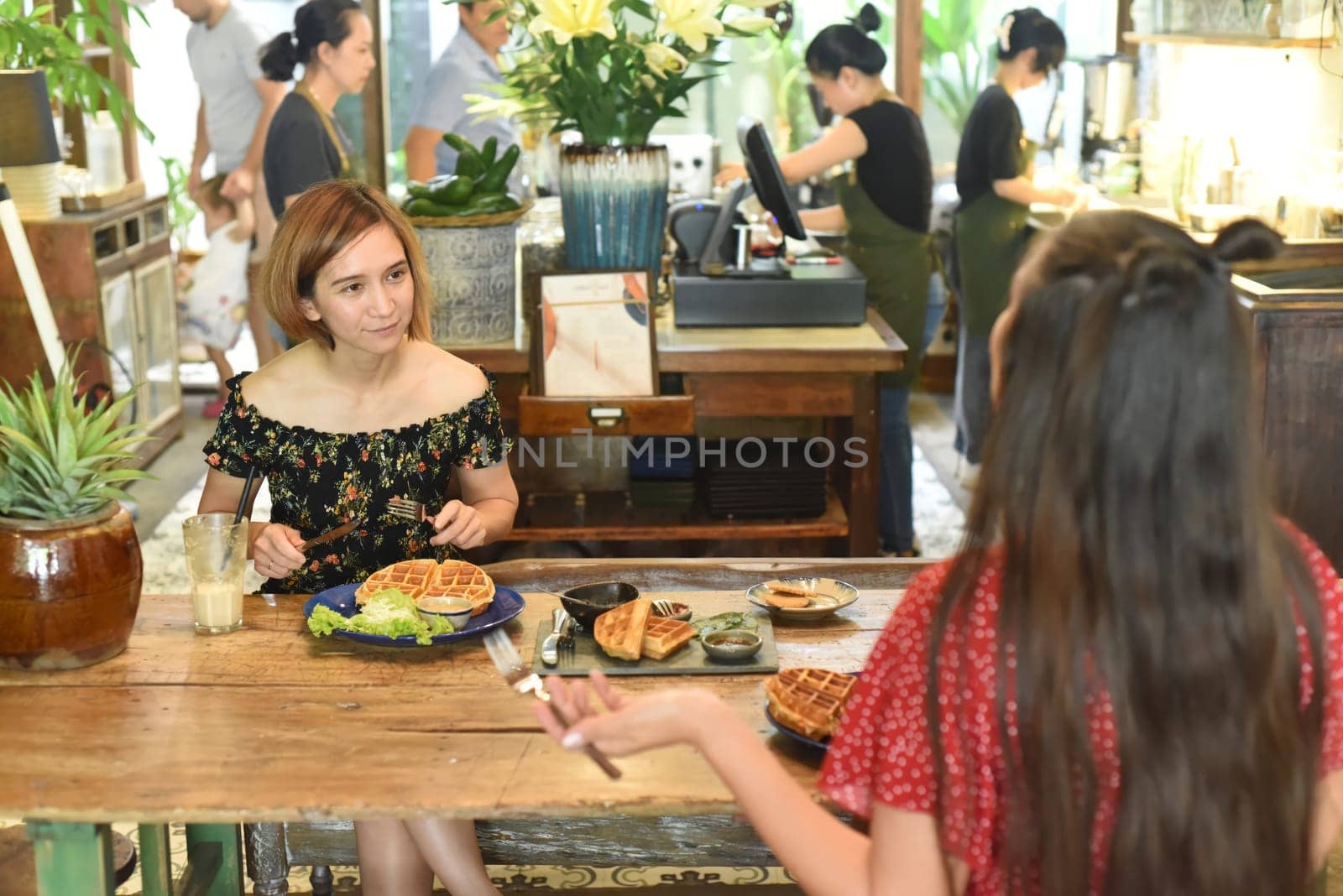 Young women chatting and eating waffles in a cafe