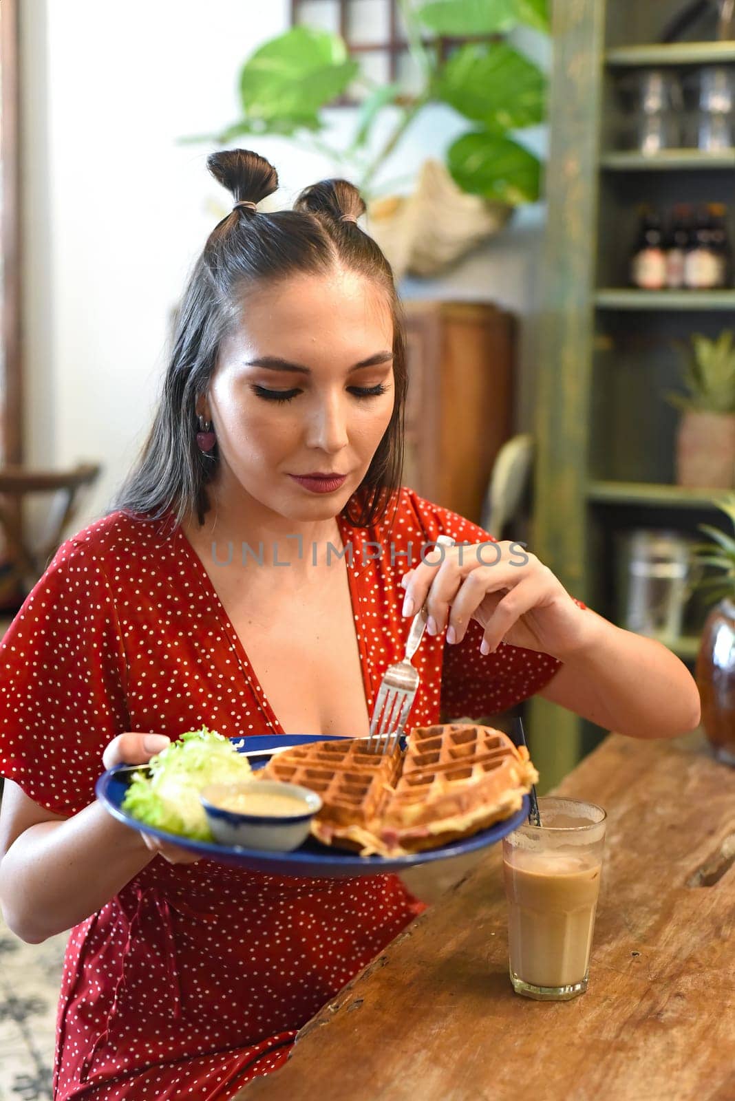 Young woman eating waffles in a coffee shop