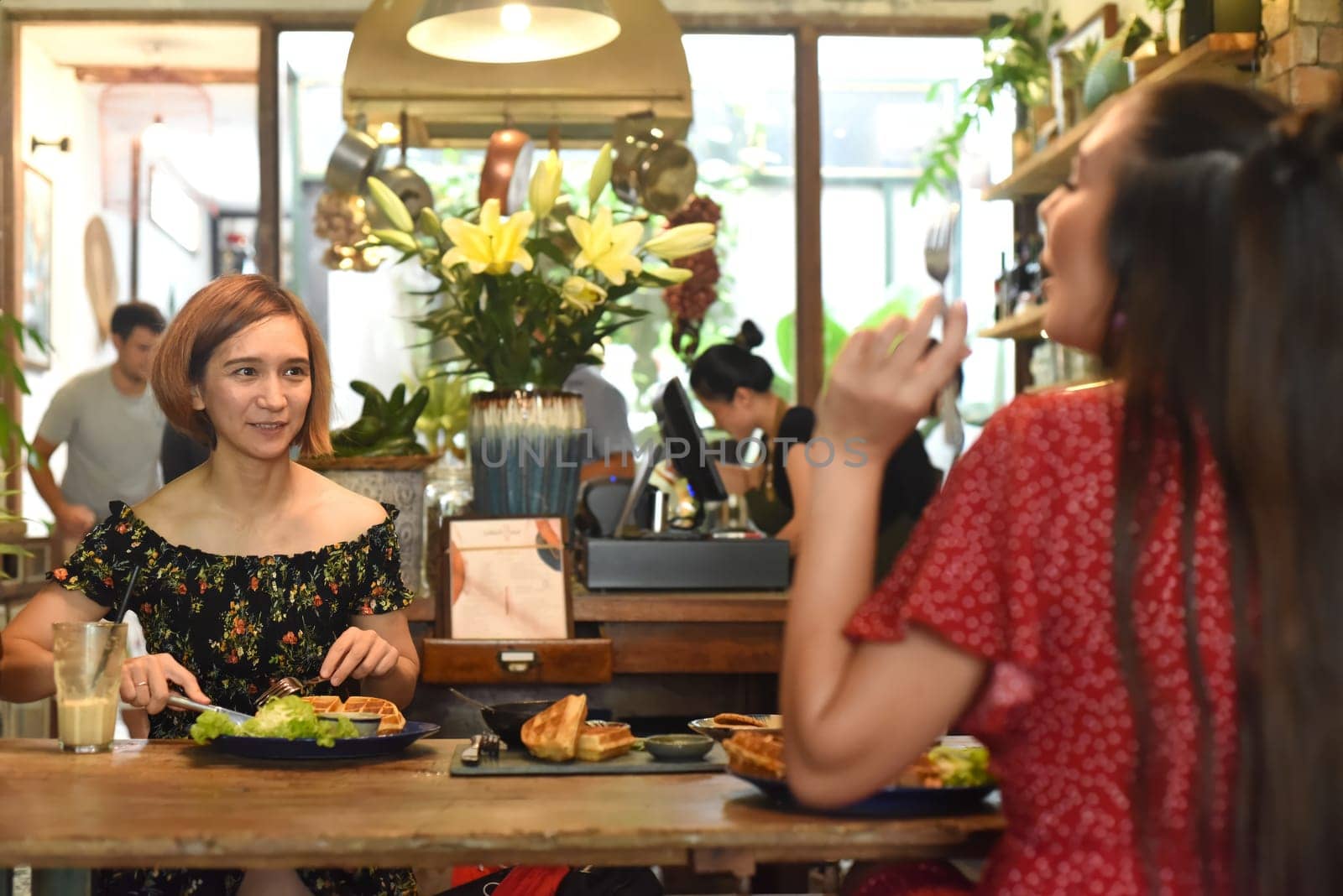 Young women chatting and eating waffles in a cafe