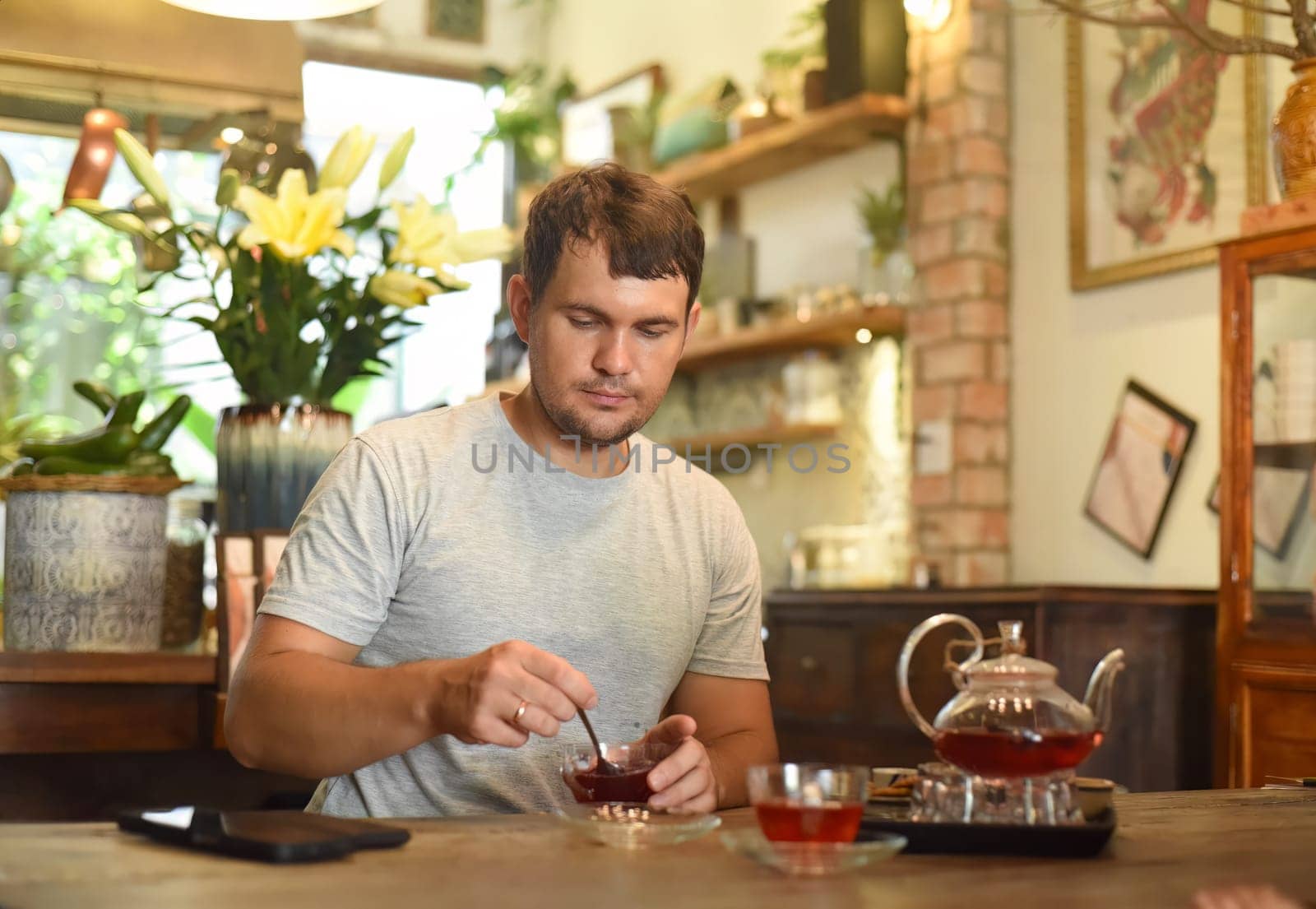 Young man eating homemade jam and tea in cafe