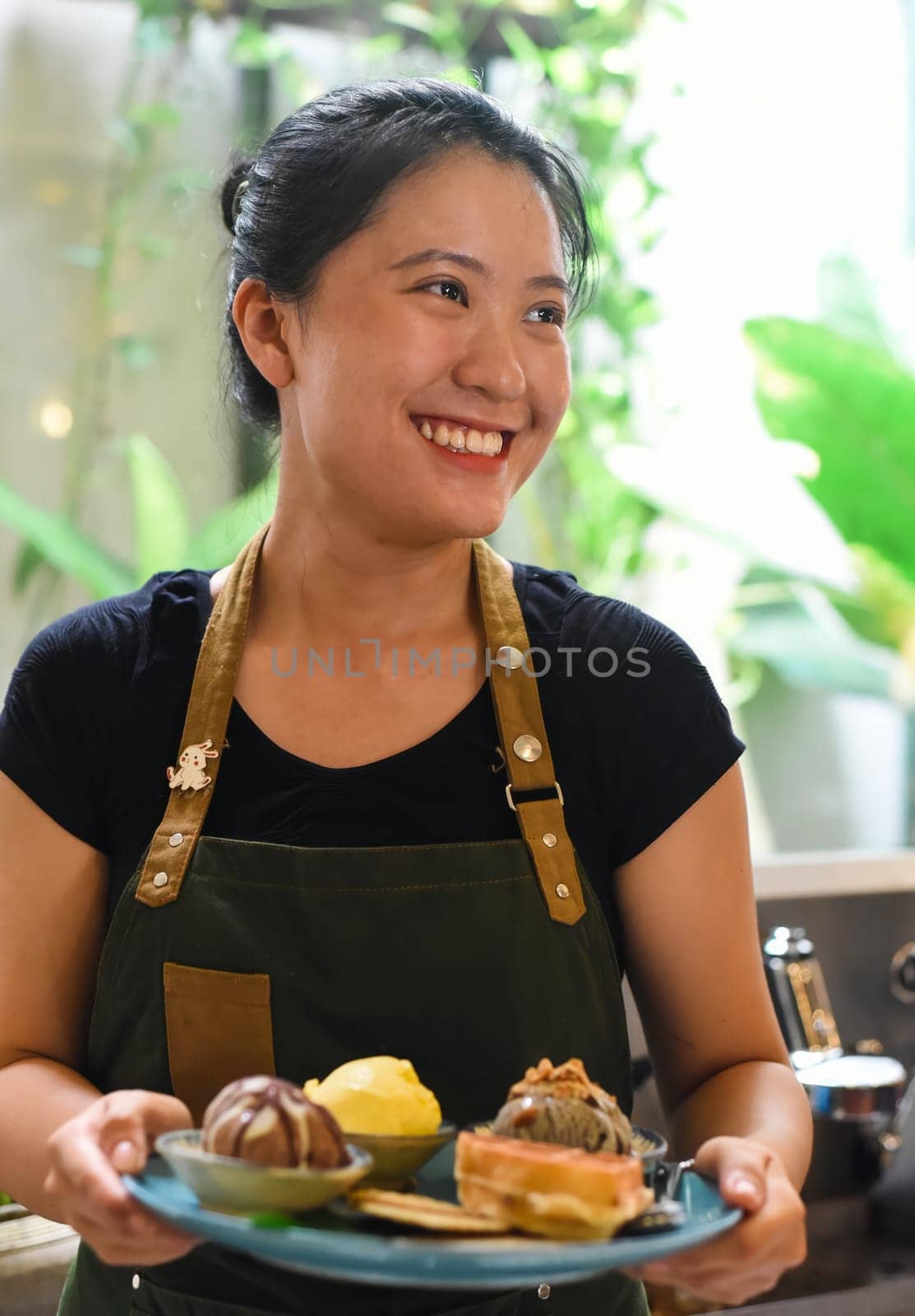 Vietnamese girl serving homemade ice cream with waffle at a coffee shop.