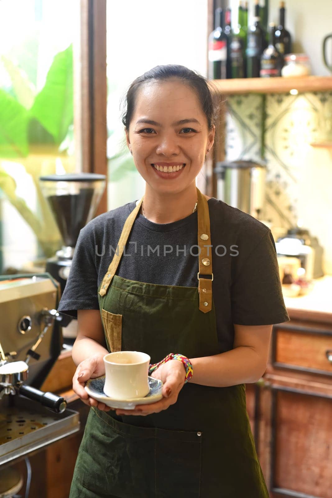 Vietnamese waitress holding cup of espresso in cafe