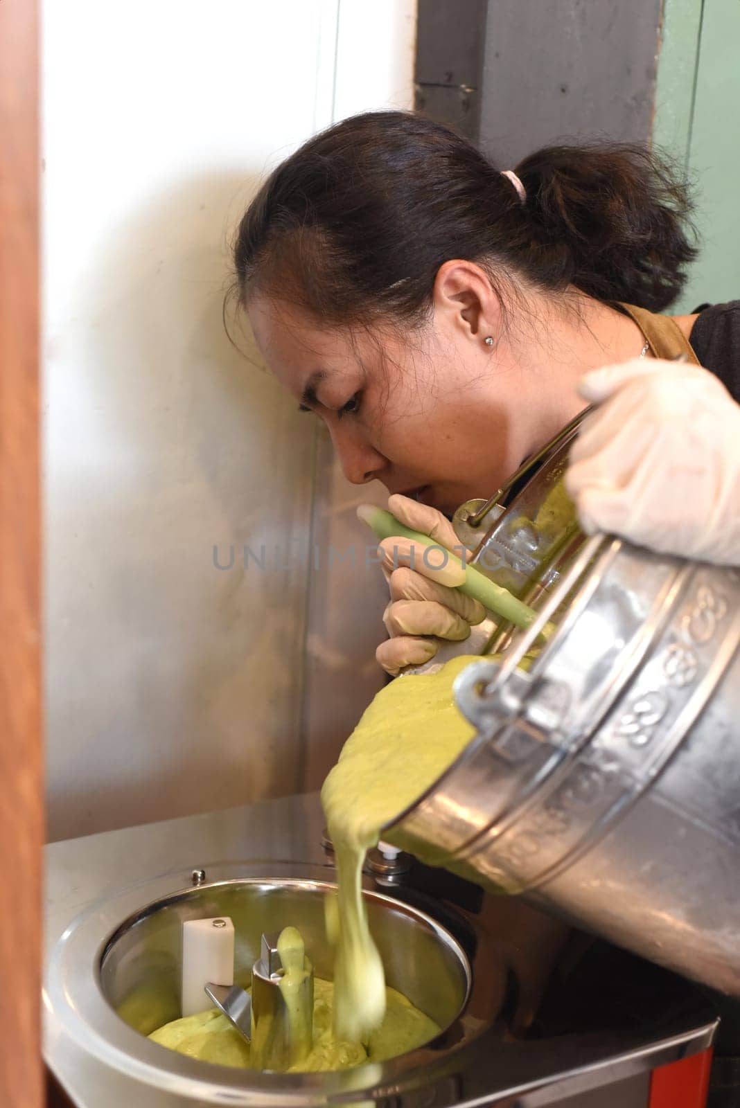 Vietnamese woman shifting home made ice cream from bucket into mixer
