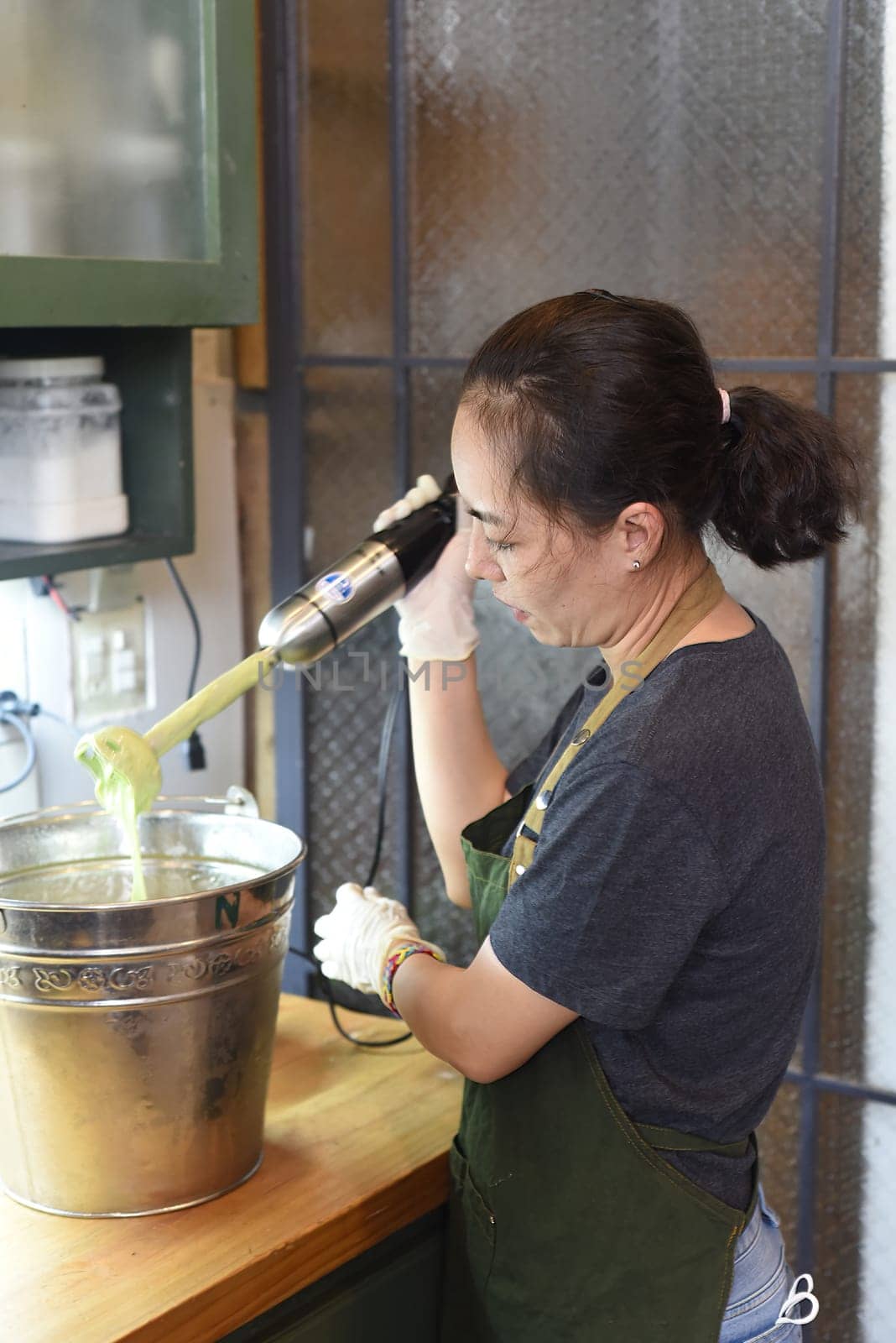 Young vietnamese woman stirs the avocado ice cream base