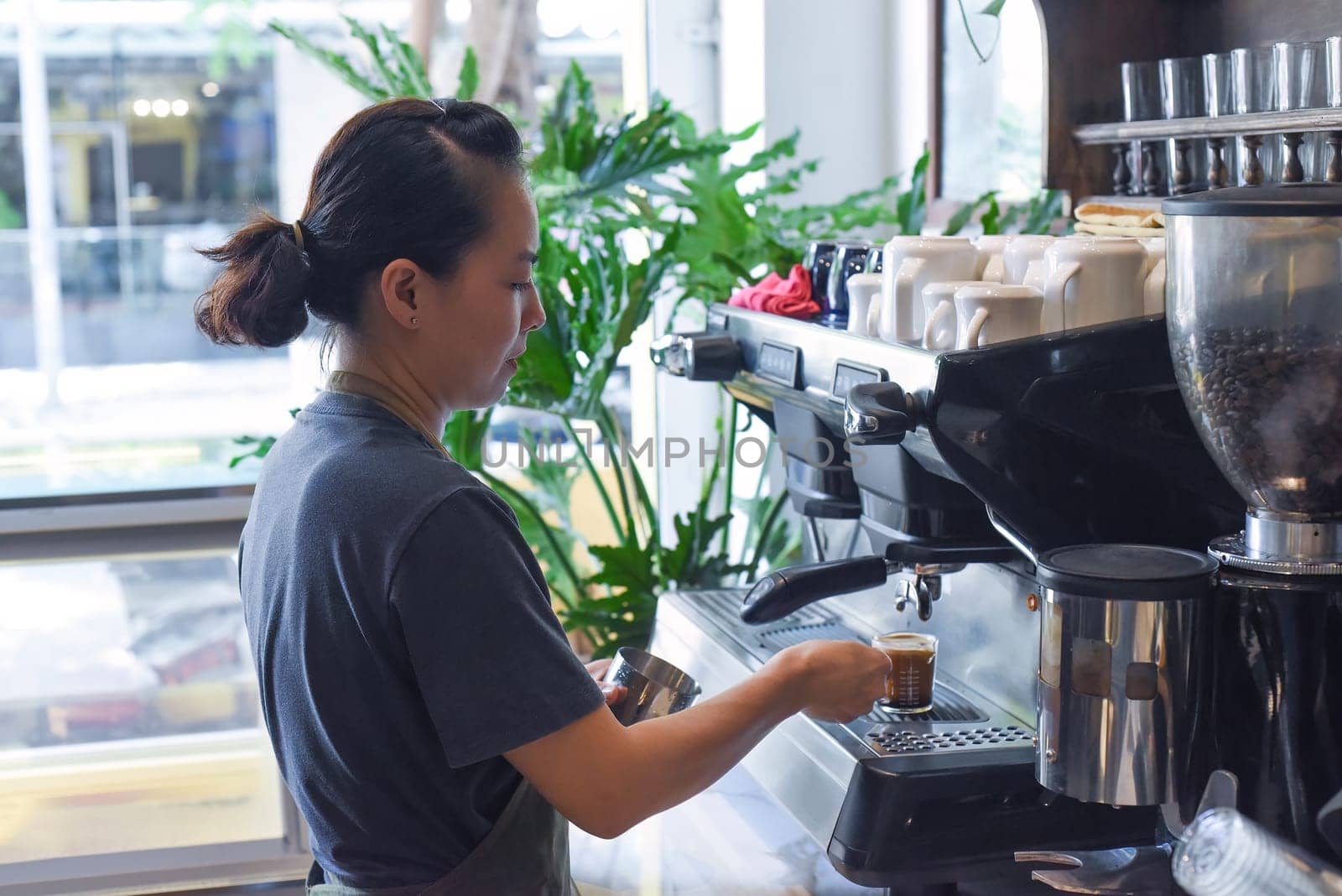 Vietnamese barista making espresso with coffee machine close up