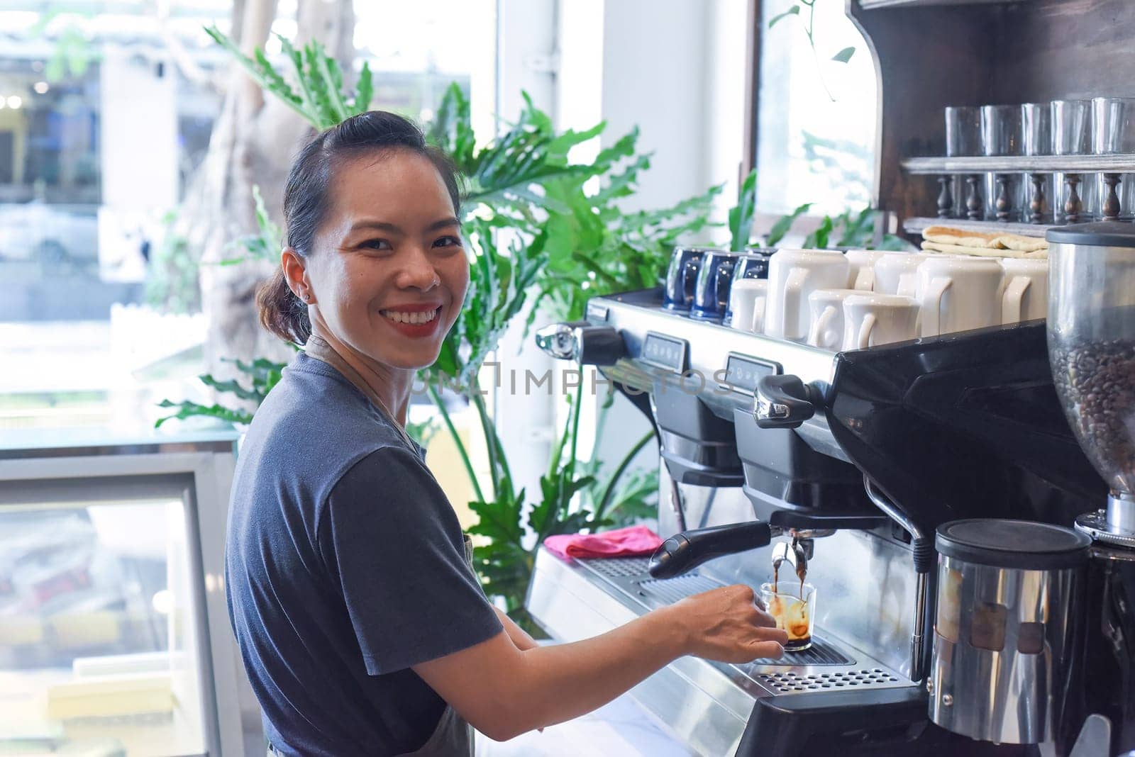 Vietnamese barista making espresso with coffee machine close up
