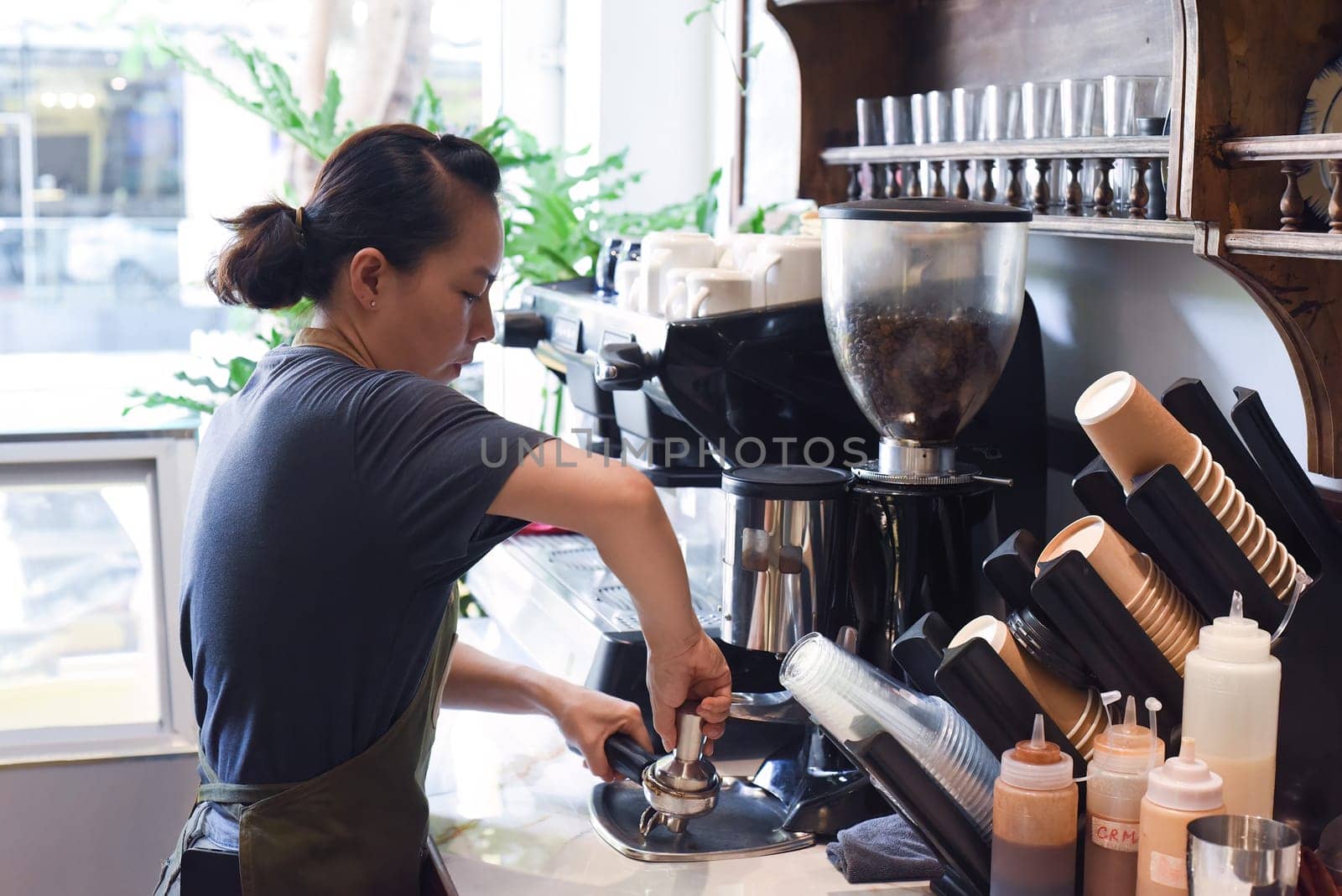 Vietnamese barista making espresso with coffee machine close up