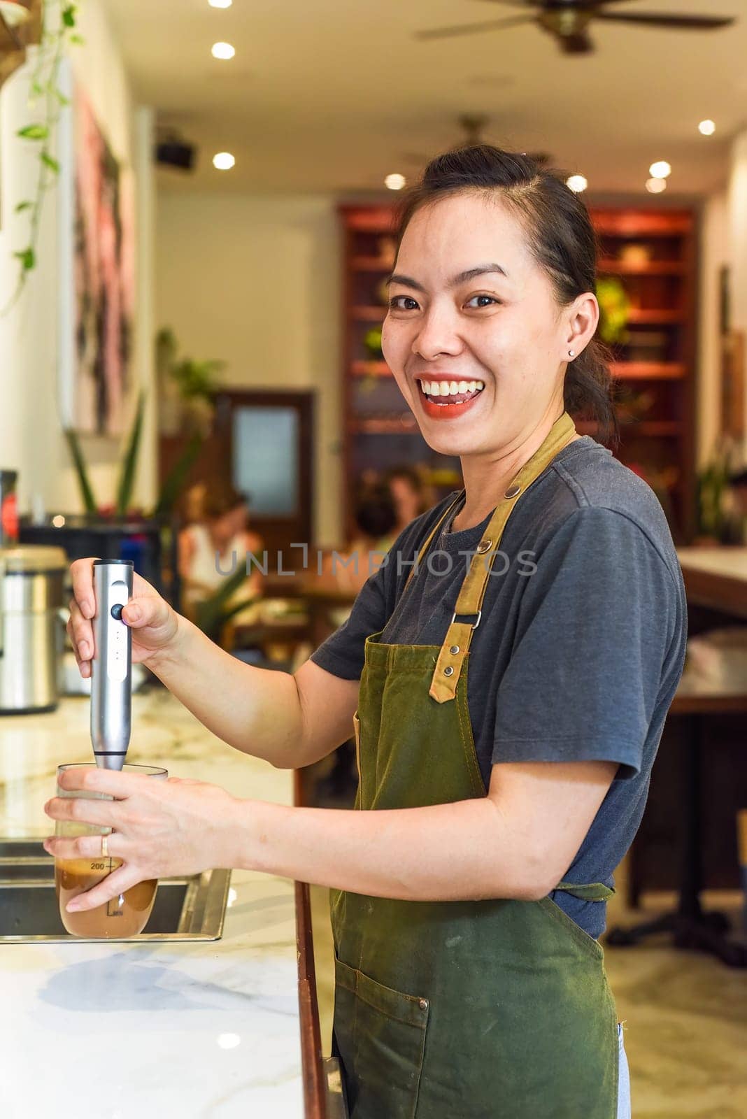 Vietnamese barista using a mixer for condensed milk in glass cup for preparing vietnamese coffee Cafe Sua
