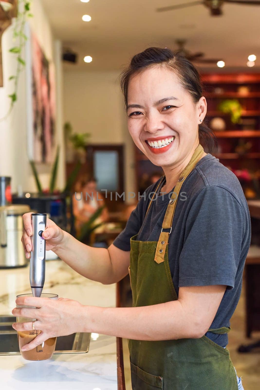 Vietnamese barista using a mixer for condensed milk in glass cup for preparing vietnamese coffee Cafe Sua