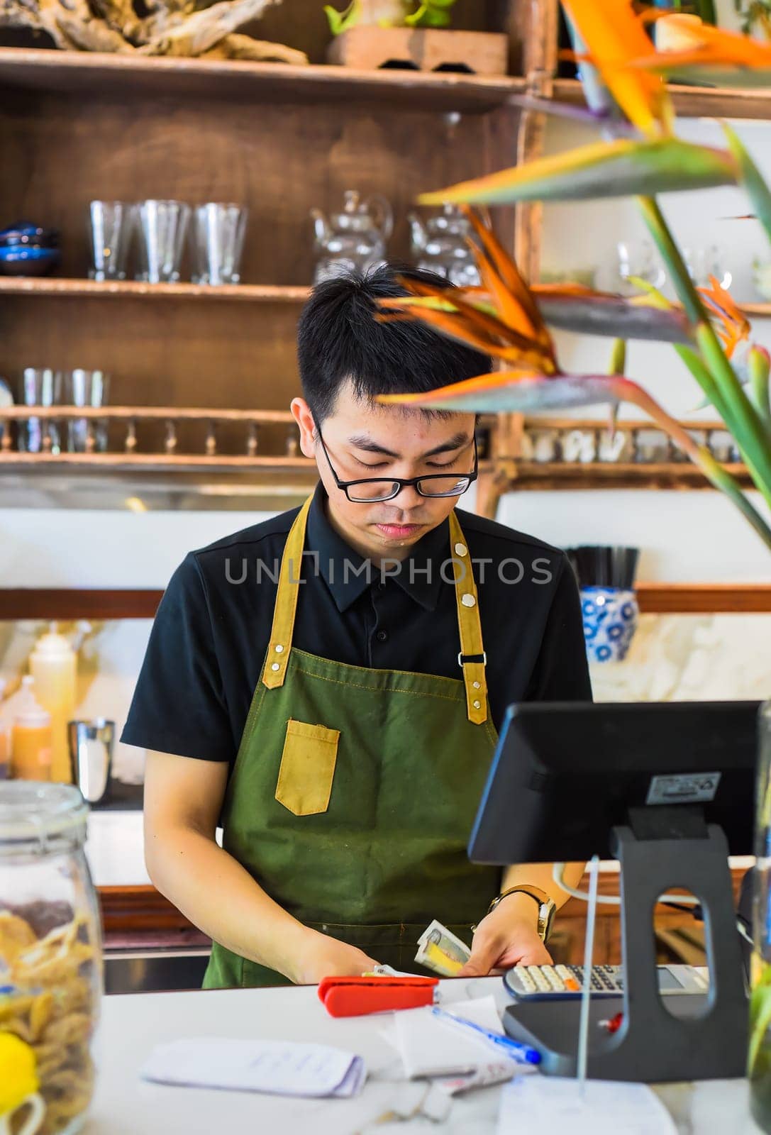 Vietnamese waiter working in counter with cashier machine in a cafe