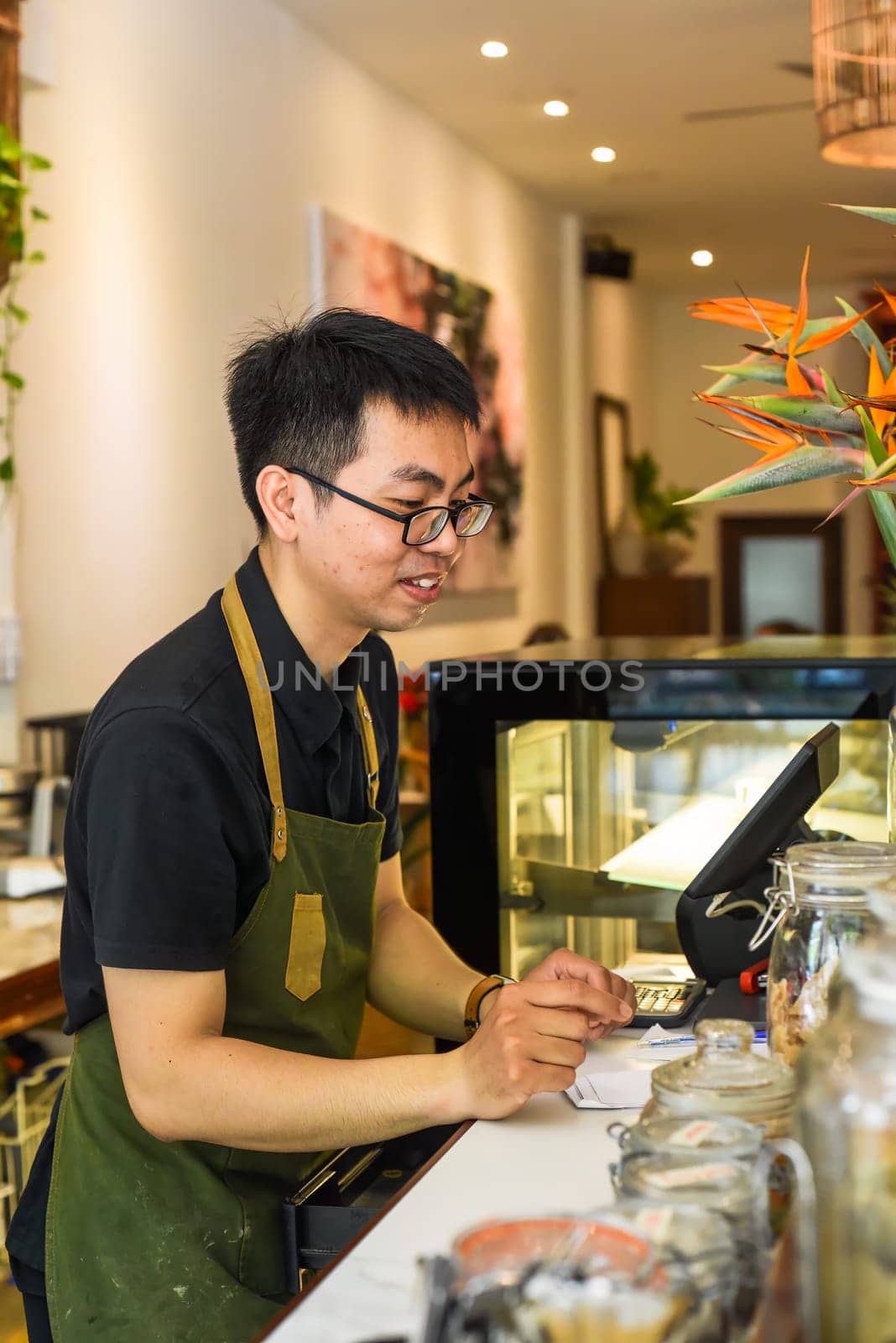 Vietnamese waiter working in counter with cashier machine in a cafe