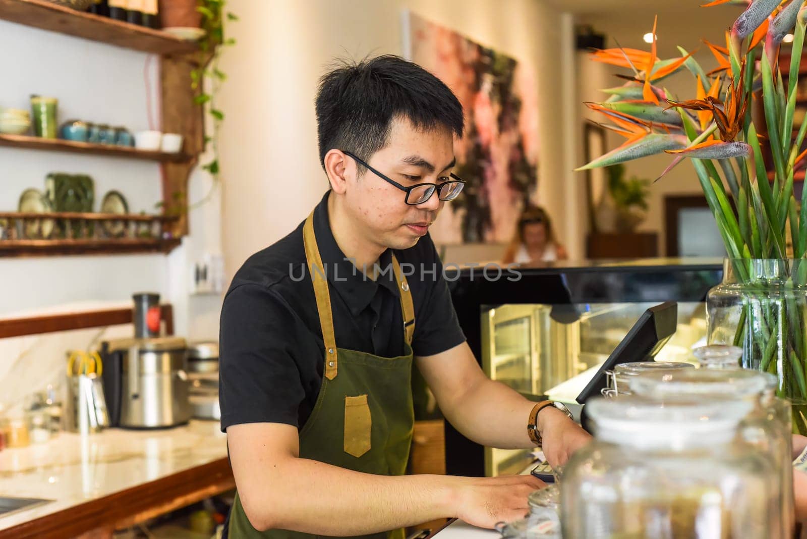Vietnamese waiter working in counter with cashier machine in a cafe
