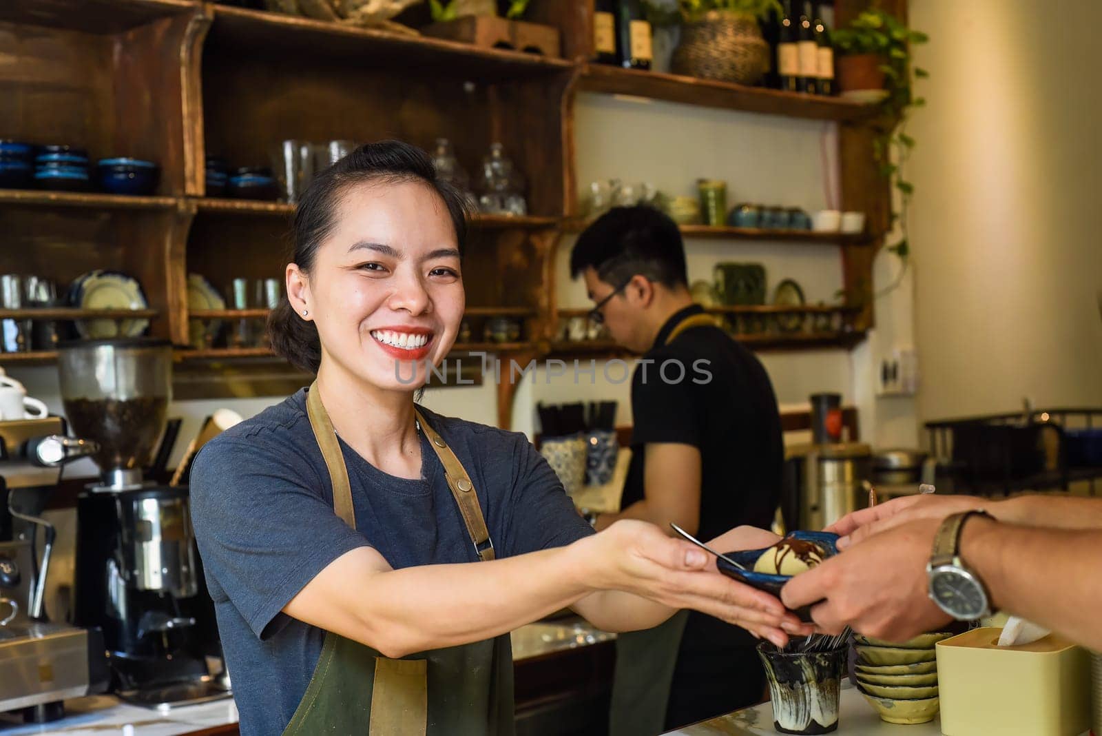 Vietnamese waitress serving ice cream for a customer in a coffee shop