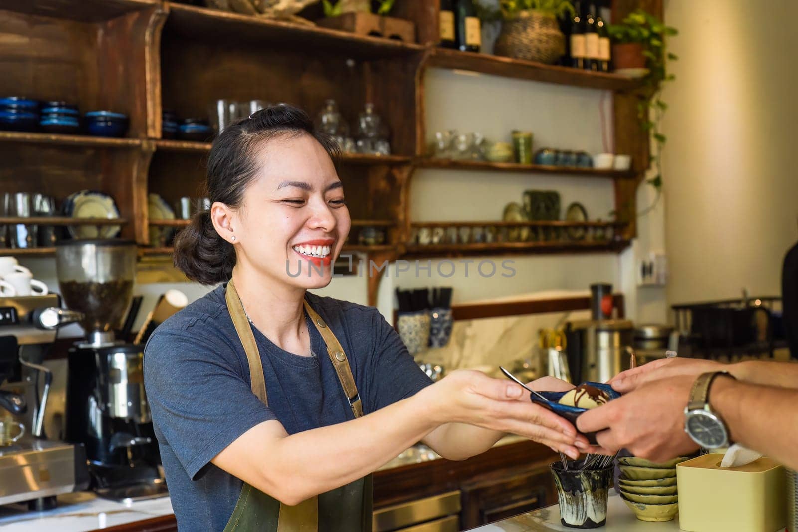 Vietnamese waitress serving ice cream for a customer in a coffee shop