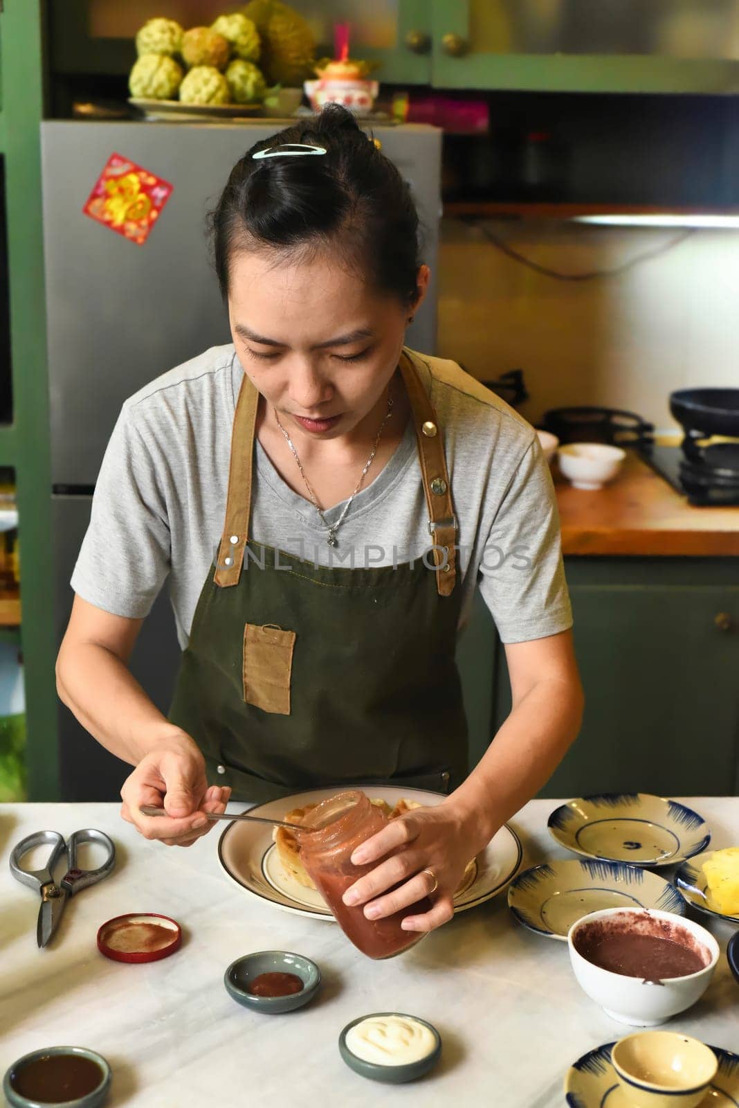 Vietnamese woman in apron serving foor on the table