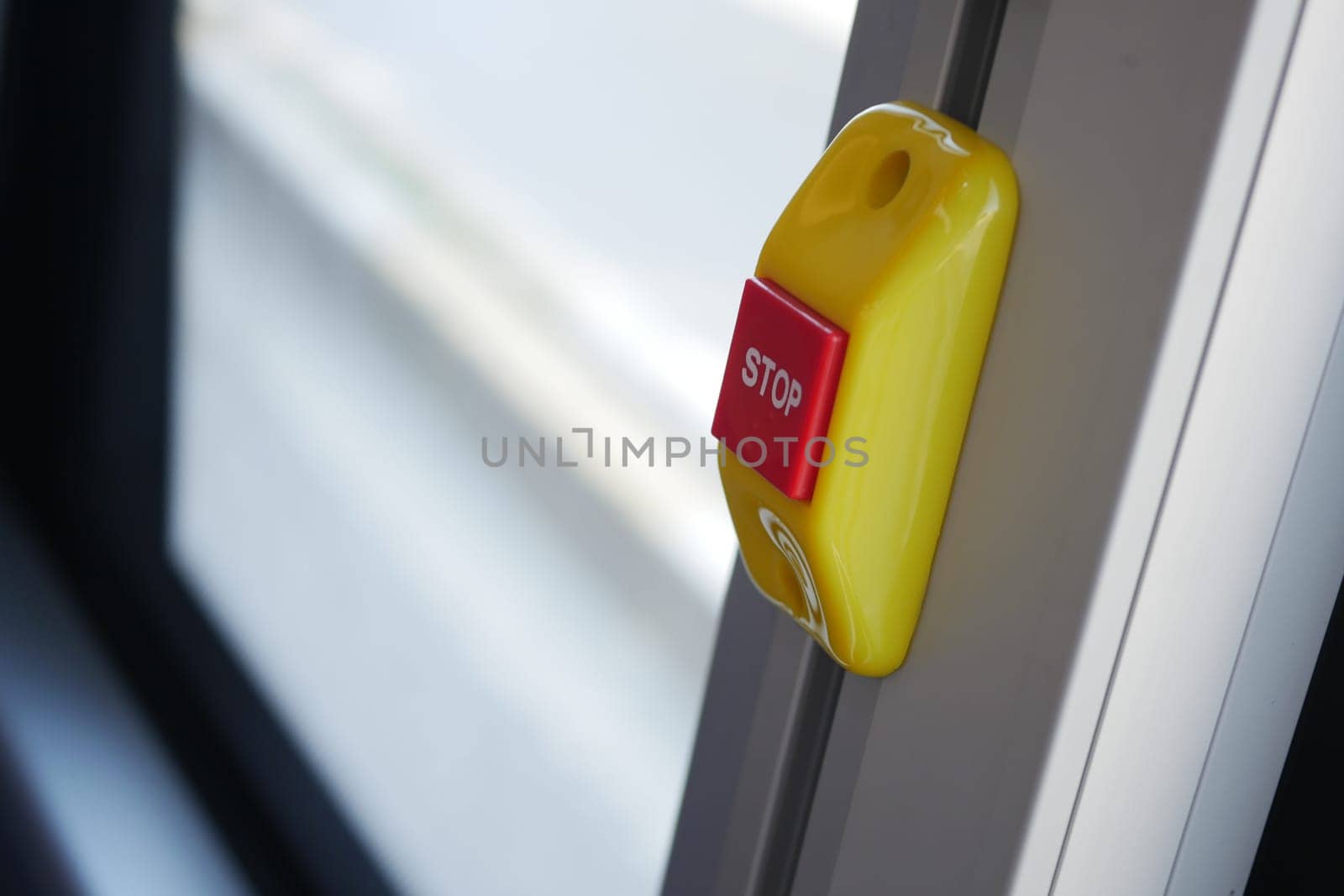 Bright yellow stop button located on the bus window for passengers.