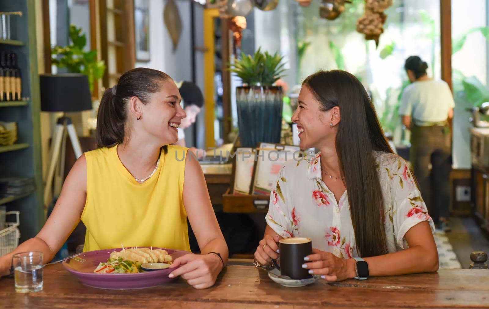 Two best friends talking and eating in a cafe