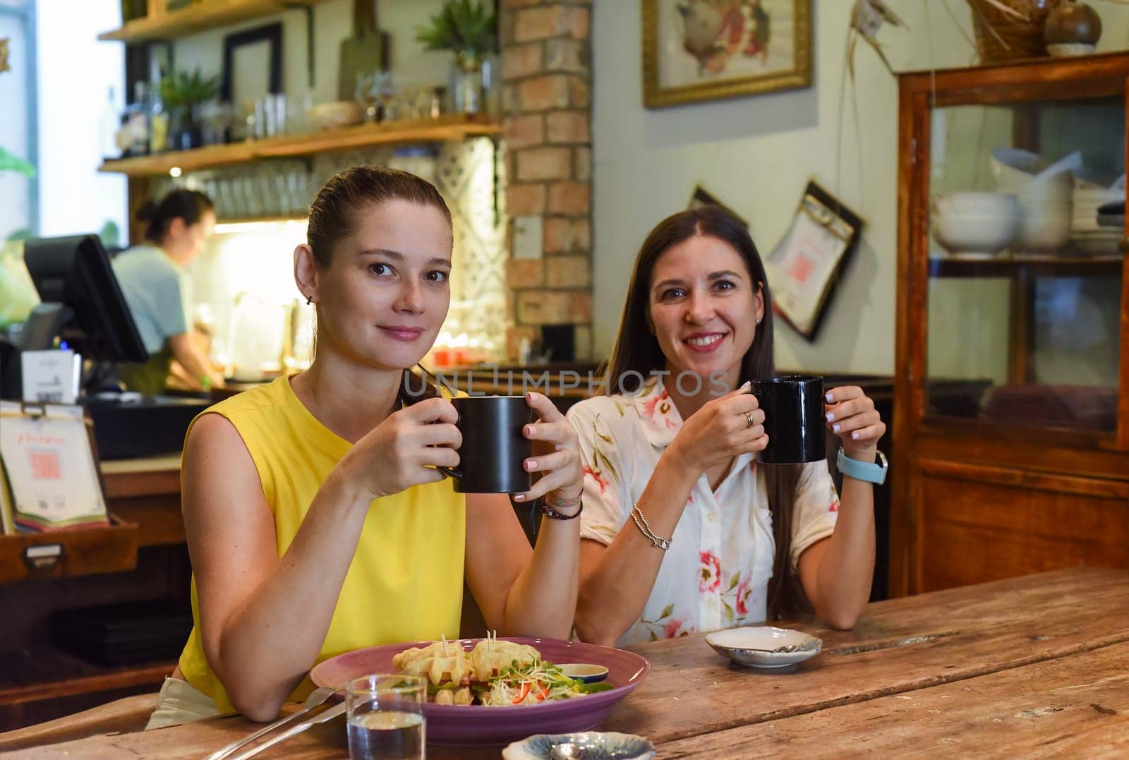 Two best friends talking and eating in a cafe