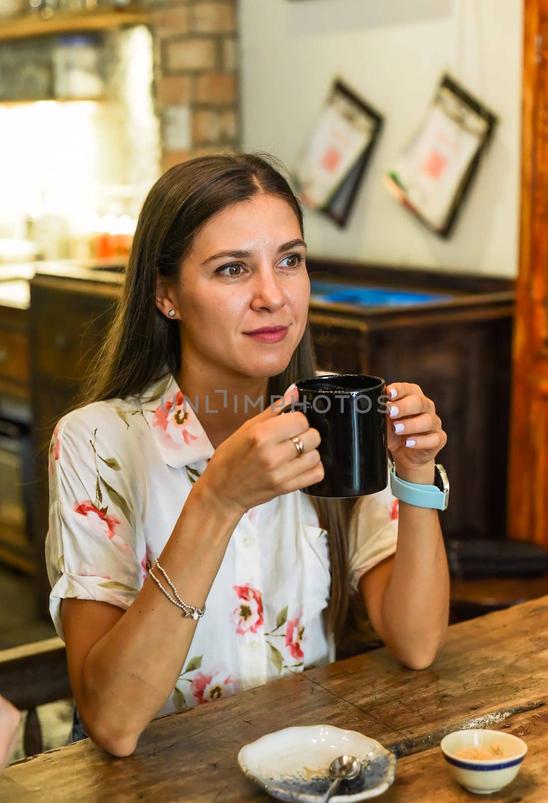 Portrait of smiling russian woman drinking hot capuccino and looking right