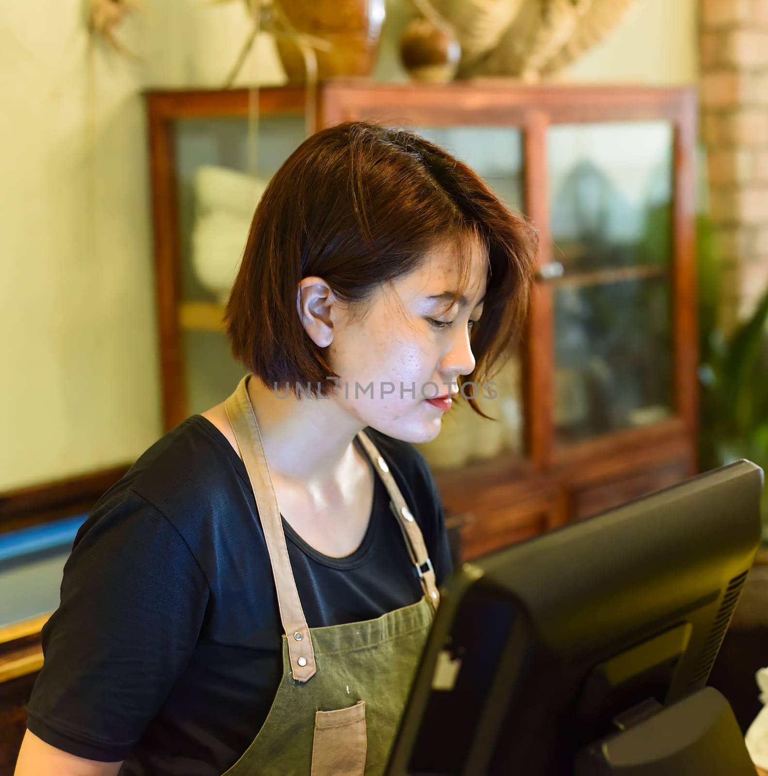 Young Vietnamese waitress working with check out machine in cafe