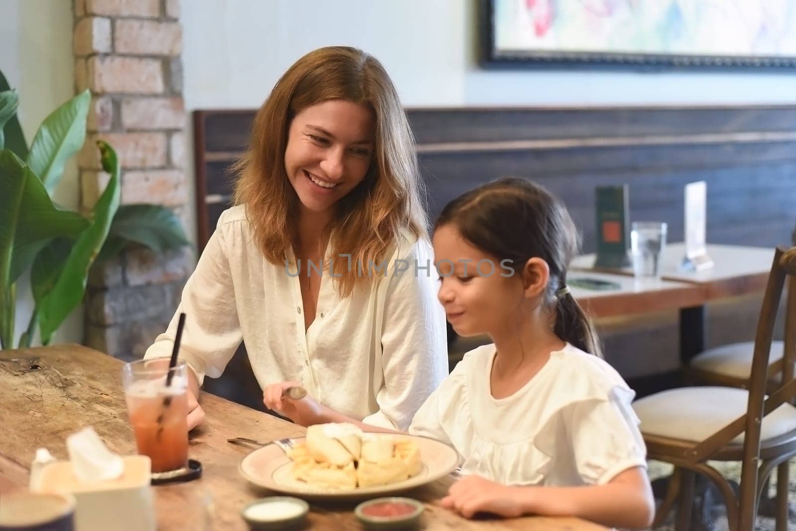 Little girl and her mother hugging and looking at each other in a cafe