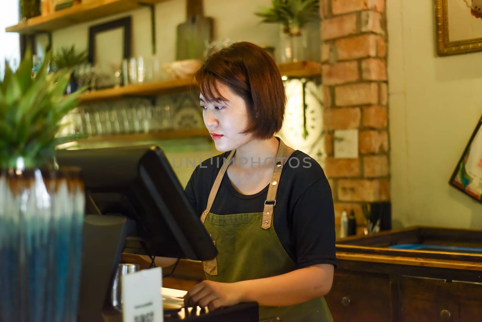 Young Vietnamese waitress working with check out machine in cafe