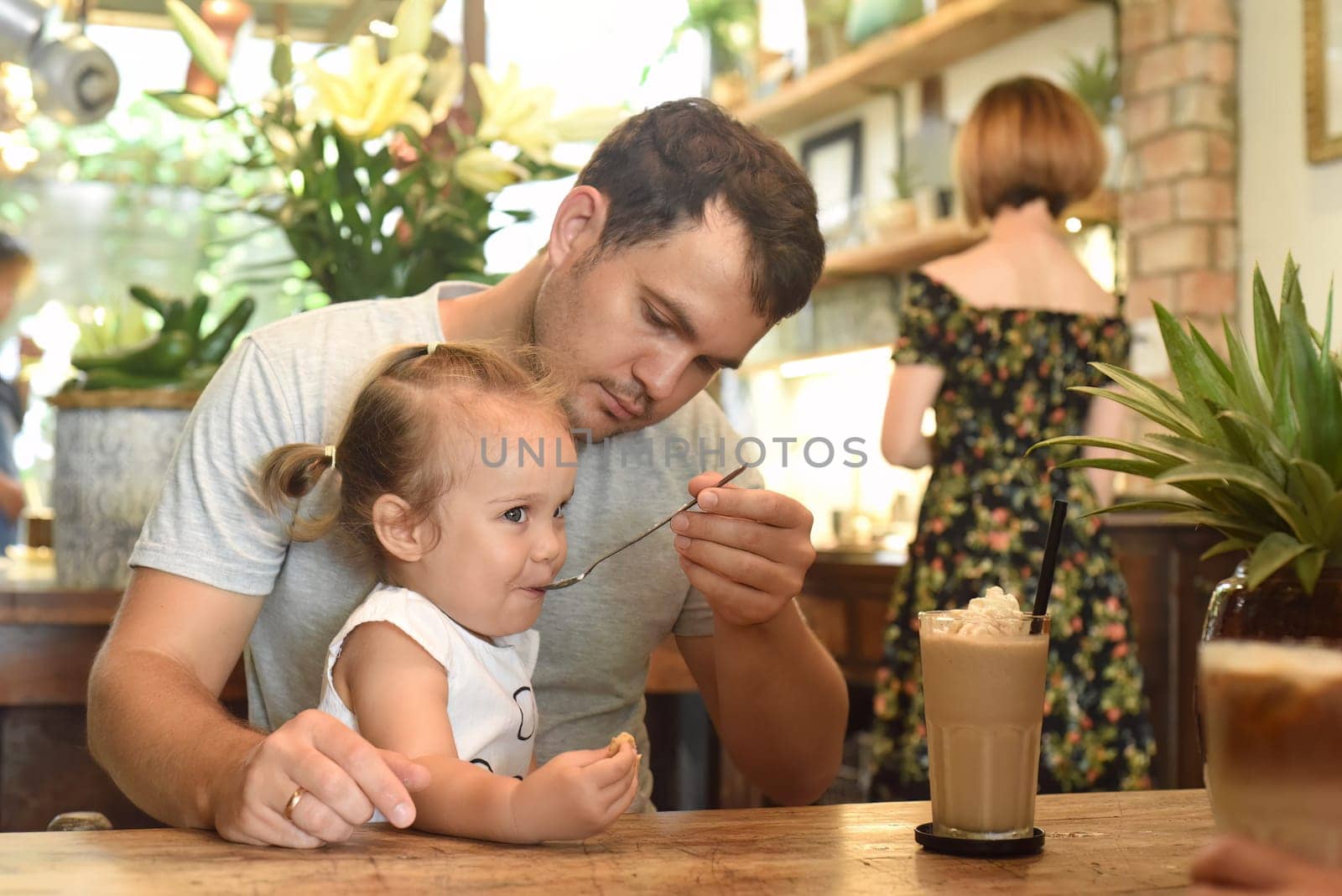 Father and daughter eating cream from frappe in a cafe