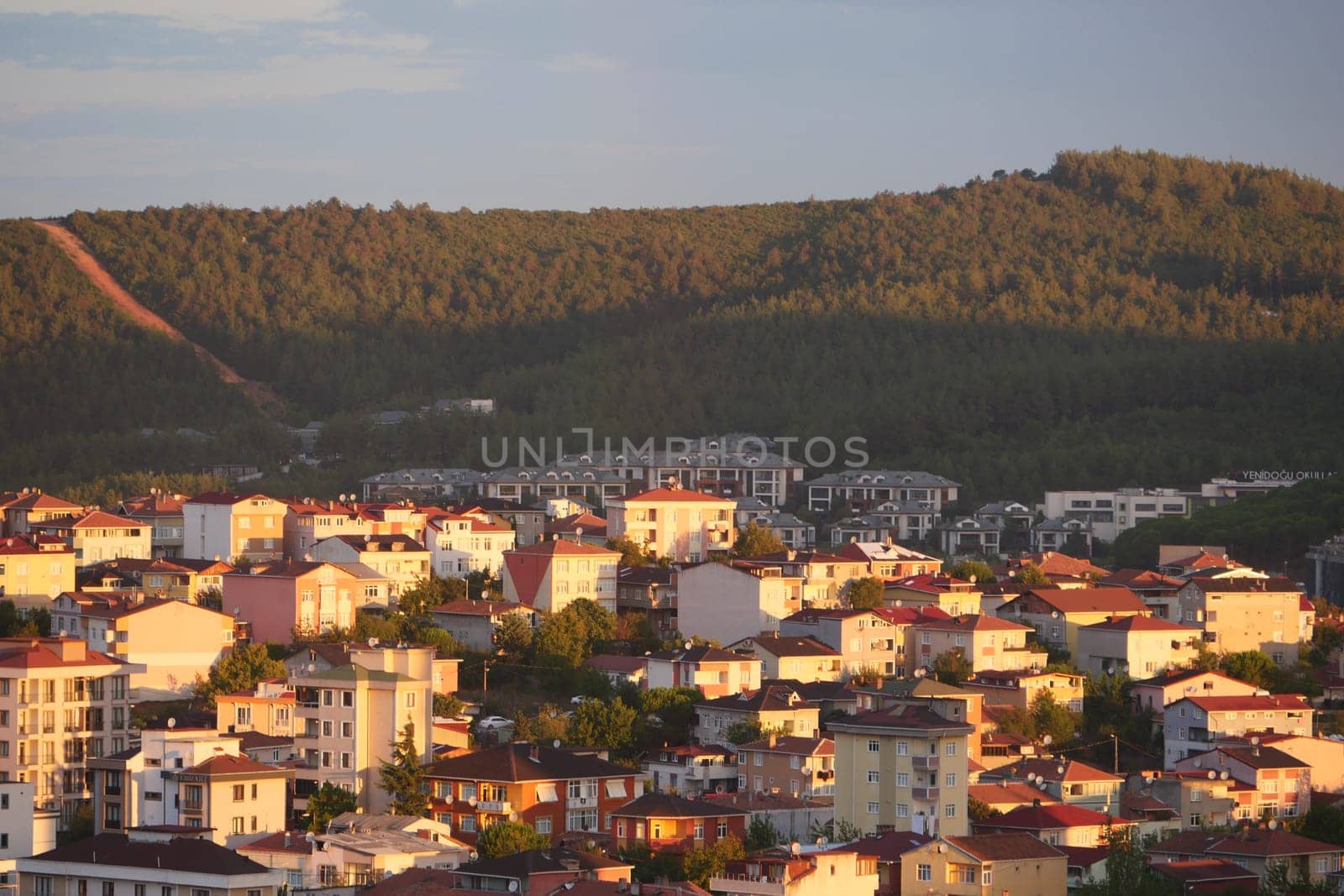 Residential buildings bask in golden sunlight with hills in the background.