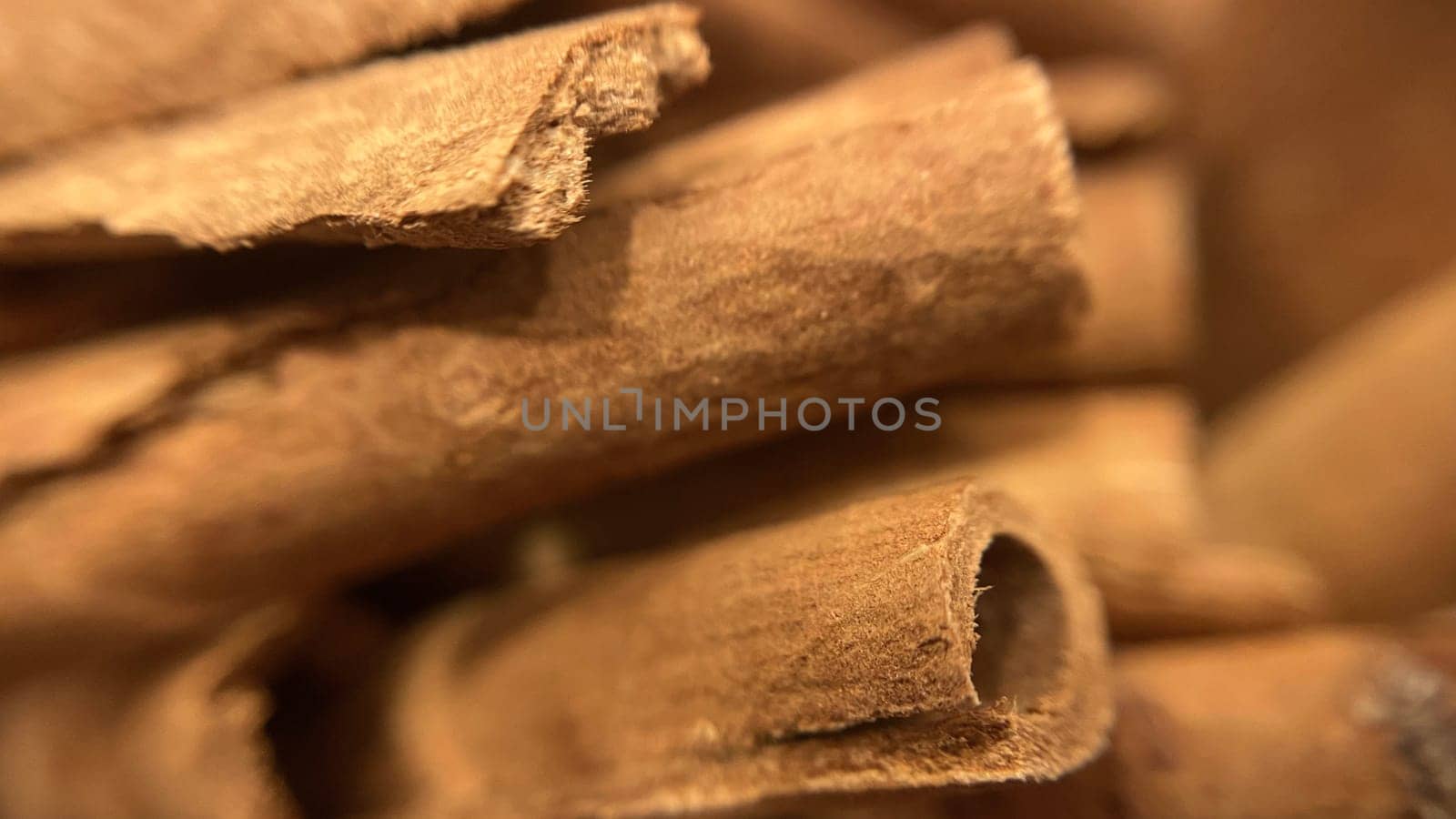 Close-up macro shot of cinnamon sticks showing rich texture and warm brown color.A detailed macro photograph of cinnamon sticks, highlighting their rough texture and curled edges. Perfect for culinary, spice, and aromatic themes.