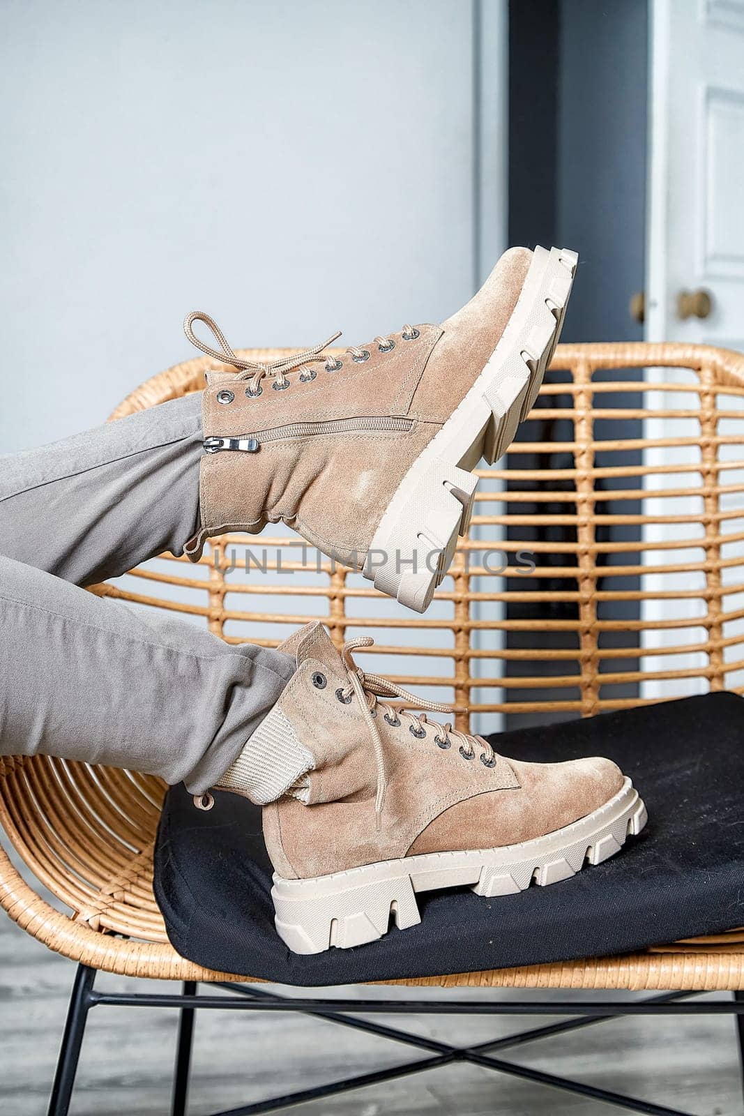 Model showcases stylish boots while lounging on a cozy chair in a contemporary indoor space, highlighting fashion trends.