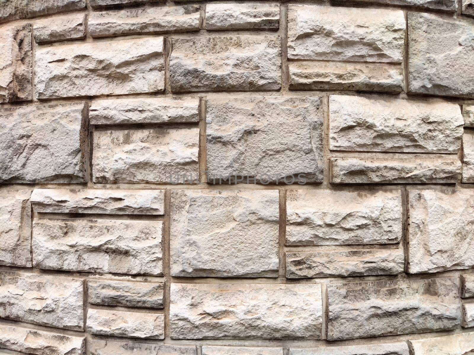 Rough textured stone wall displays a mix of light and dark shades, providing an ideal backdrop for custom text and designs.
