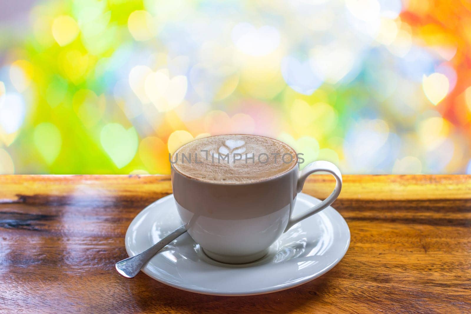 Coffee in white cup on wood table and Love abstract bokeh background heart shape of light for celebration valentine's day and wedding anniversary