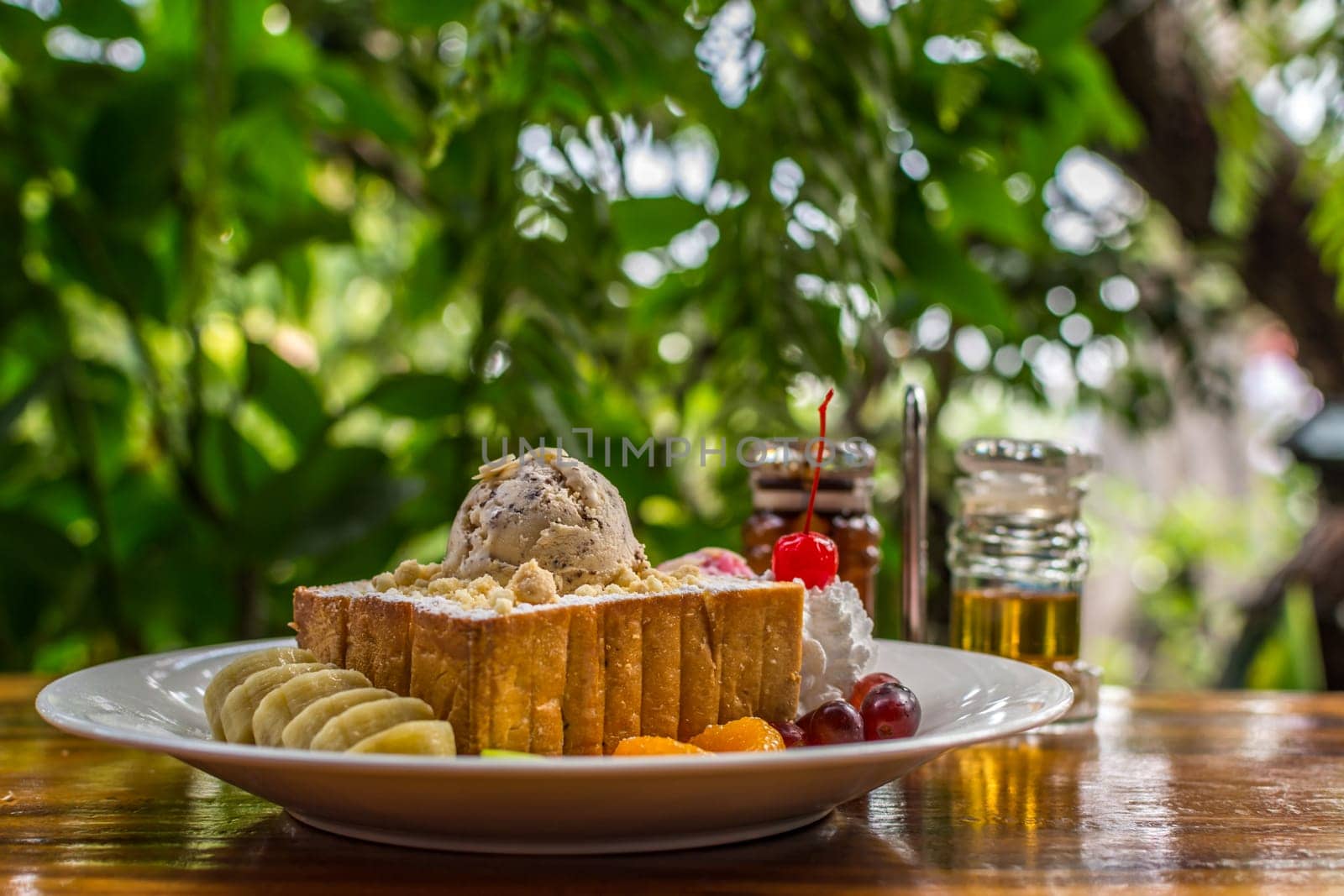 Honey toast with icecream and fruit topped with chocolate syrup and honey is a dessert tasty sweet