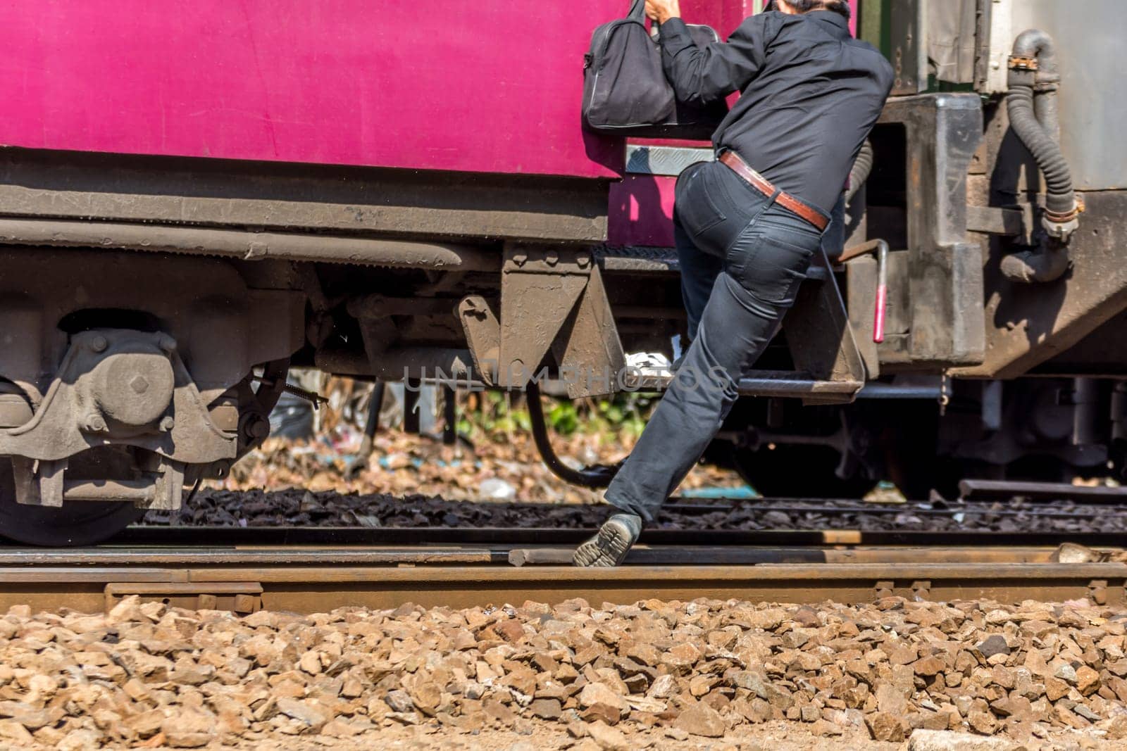 People step up to railway train on the railroad tracks in Bangkok station. Many people in Thailand popular travel by train because it is cheaper.