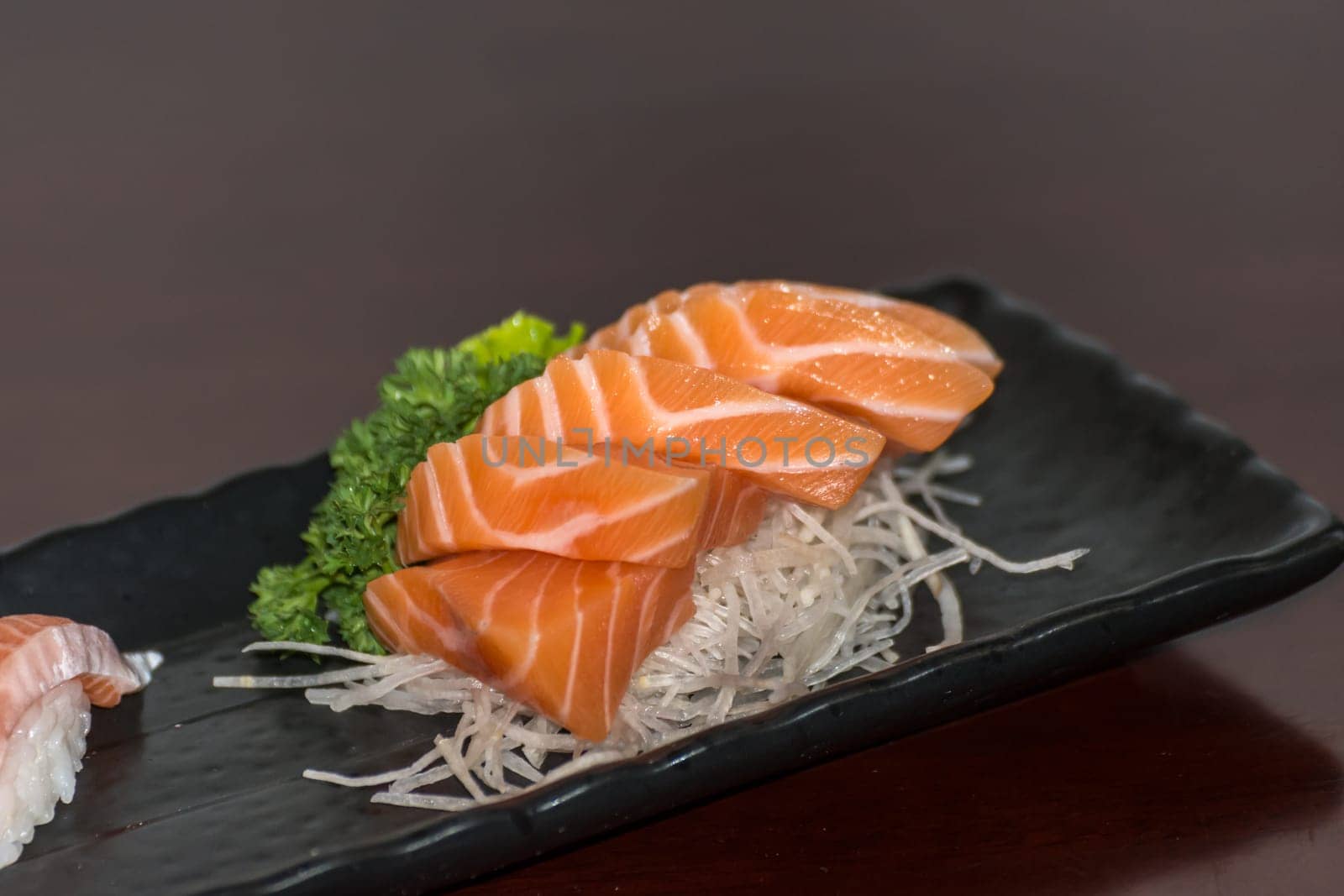 Japanese food delicacy consisting sashimi salmon of very fresh raw salmon fish sliced into thin pieces serving with radish sliced in japanese restaurant