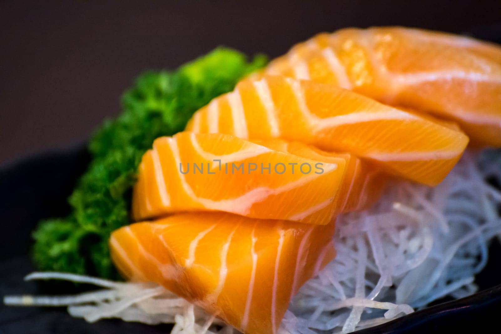Japanese food delicacy consisting sashimi salmon of very fresh raw salmon fish sliced into thin pieces serving with radish sliced in japanese restaurant