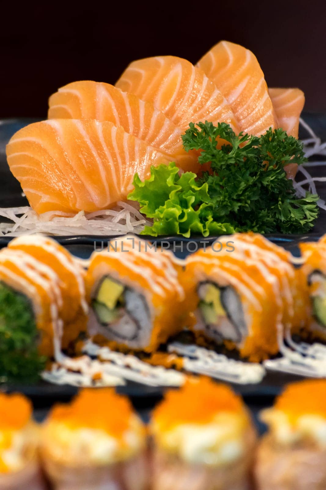 Japanese food sashimi salmon and set different types of sushi with seaweed salad and gari (ginger) is a healthy food at the upper right of the serving board in japanese restaurant