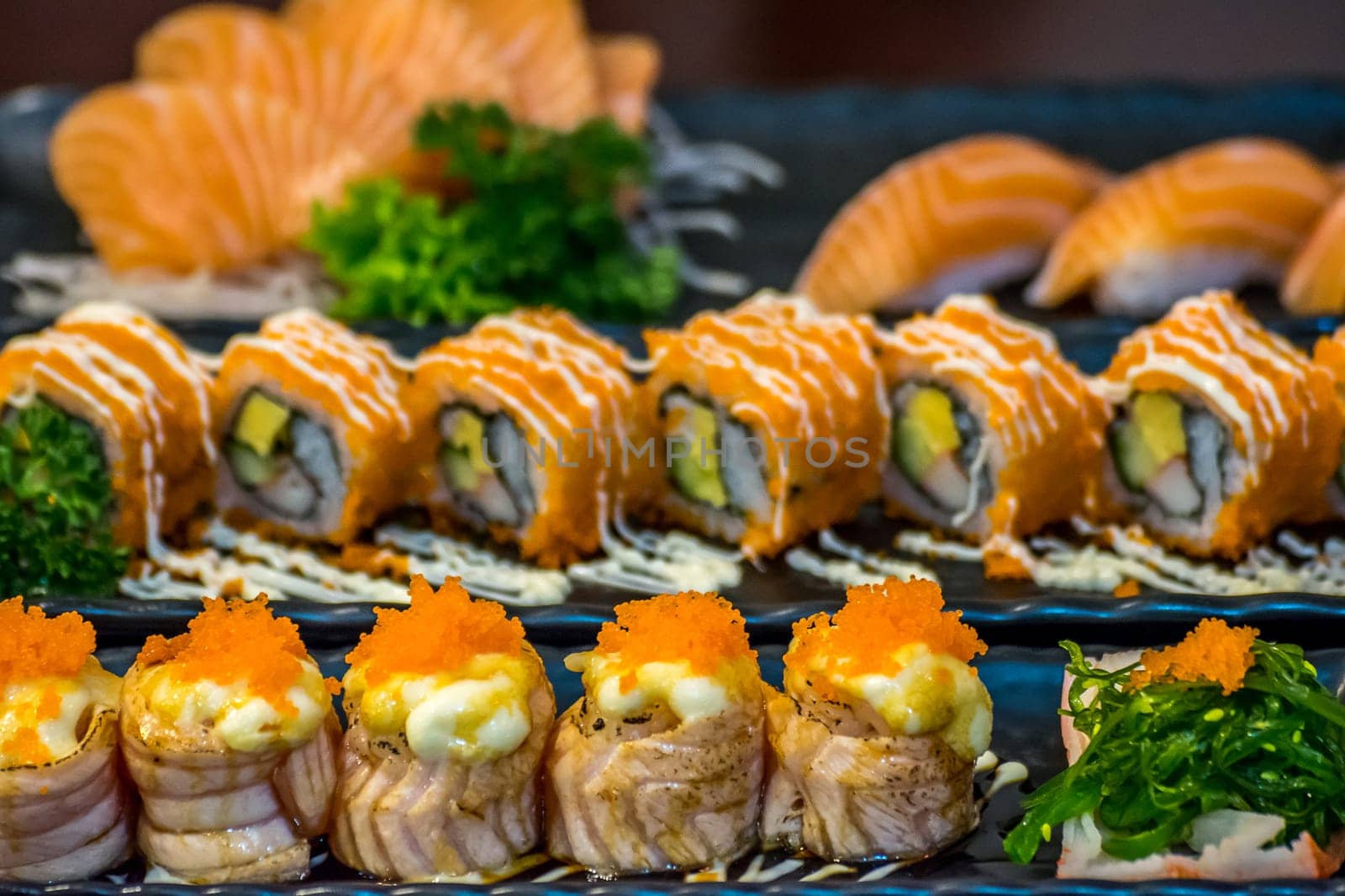 Japanese food in set different types of sushi with seaweed salad and gari (ginger) is a healthy food at the upper right of the serving board in japanese restaurant