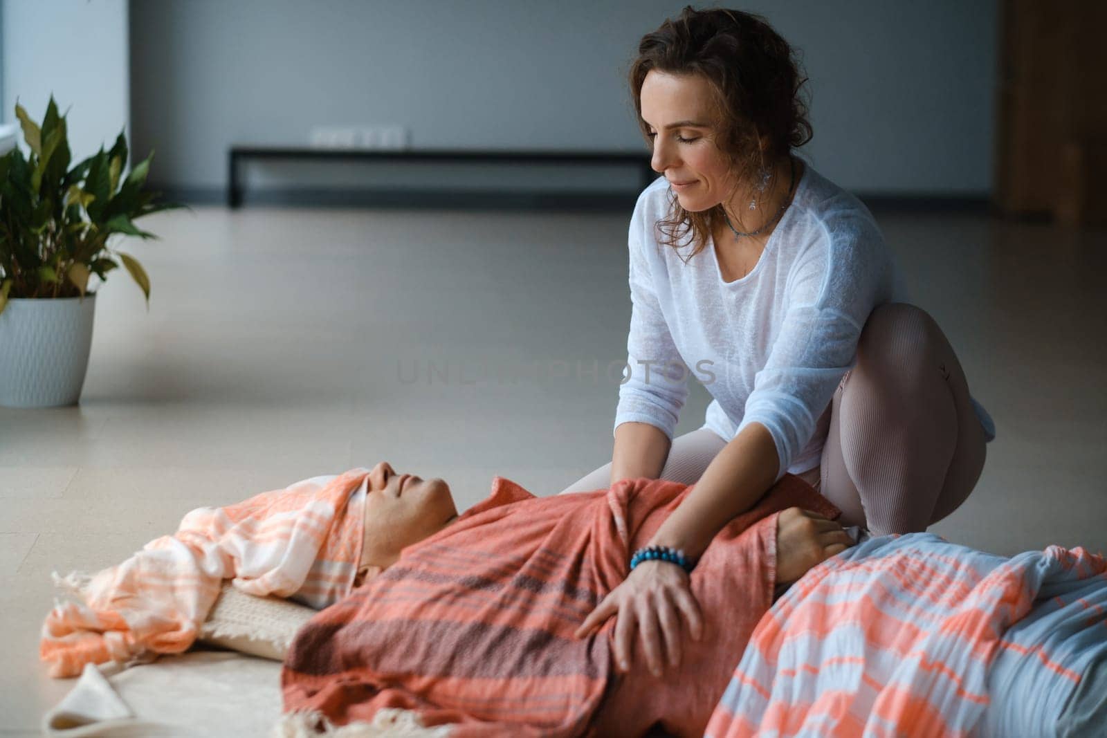 A person receives a calming head massage while lying on a soft surface, surrounded by warm colors. The atmosphere is tranquil and inviting, promoting relaxation and a sense of well-being during the session.