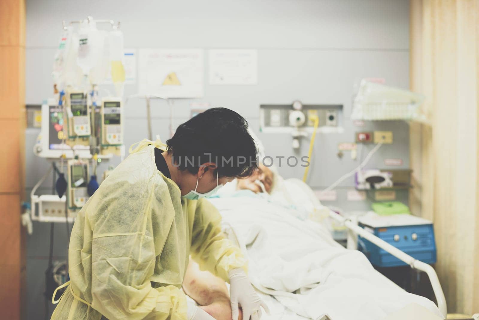 Asian women 40s years old is a patient relative taking care of the CRE. or VRE. infected elder patient 80s years old on patient bed in intensive care unit (ICU.) room at hospital.